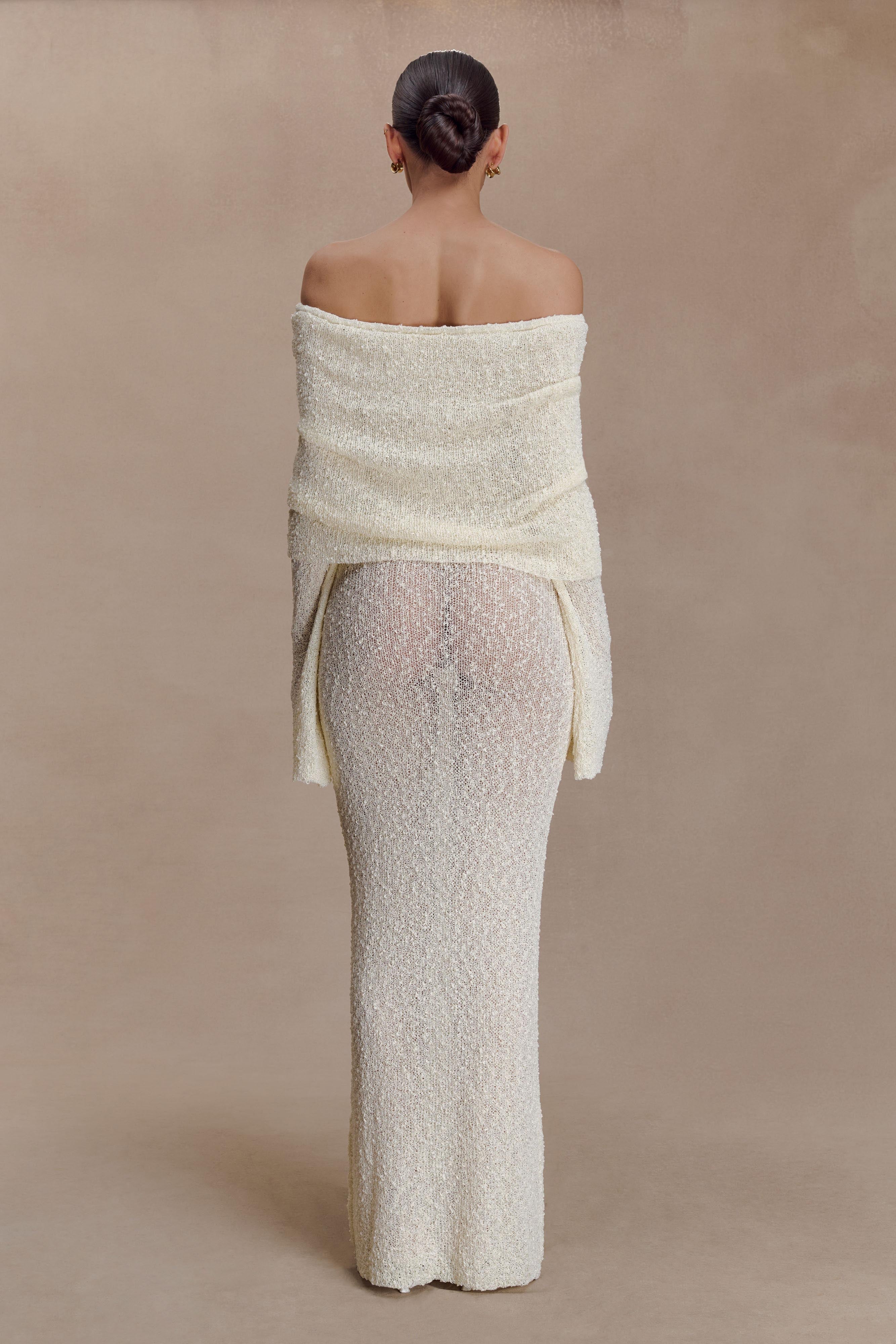 Back view of off-white off-shoulder knit maxi dress with long sleeves and draped foldover