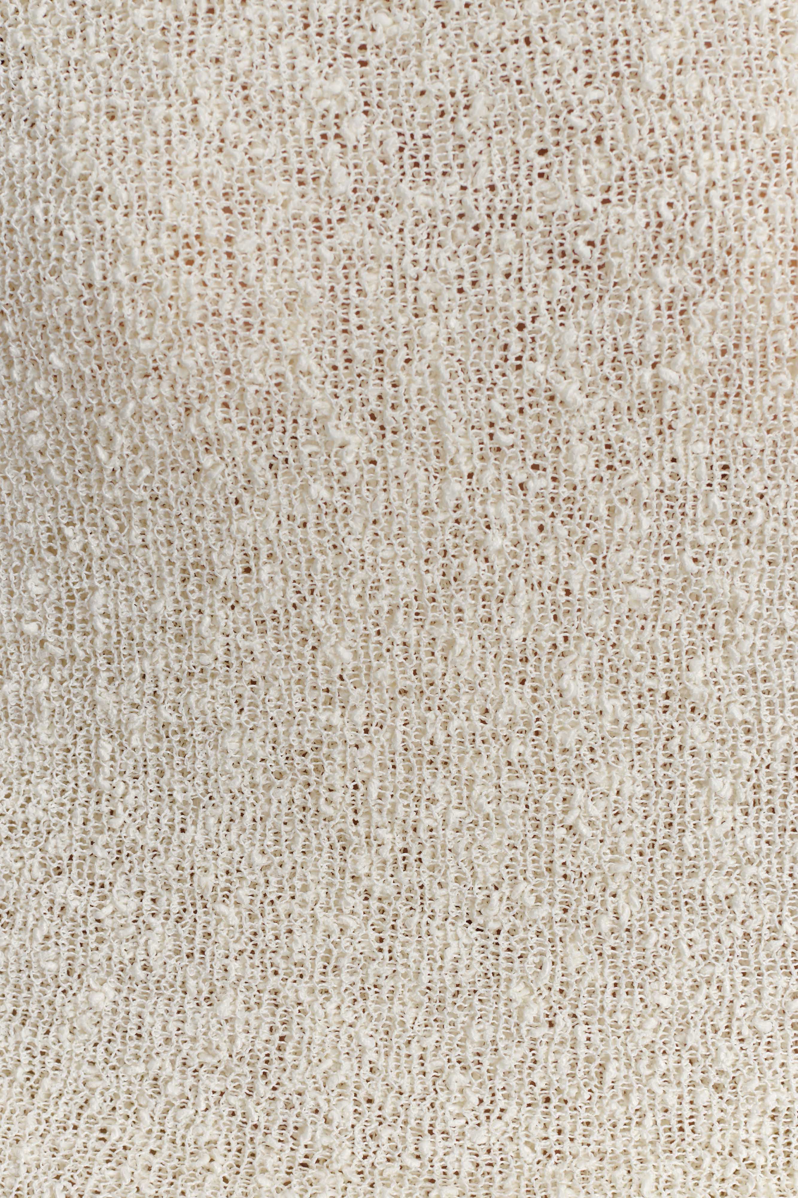 Close-up of off-white textured knit fabric for an off-shoulder maxi bodycon dress