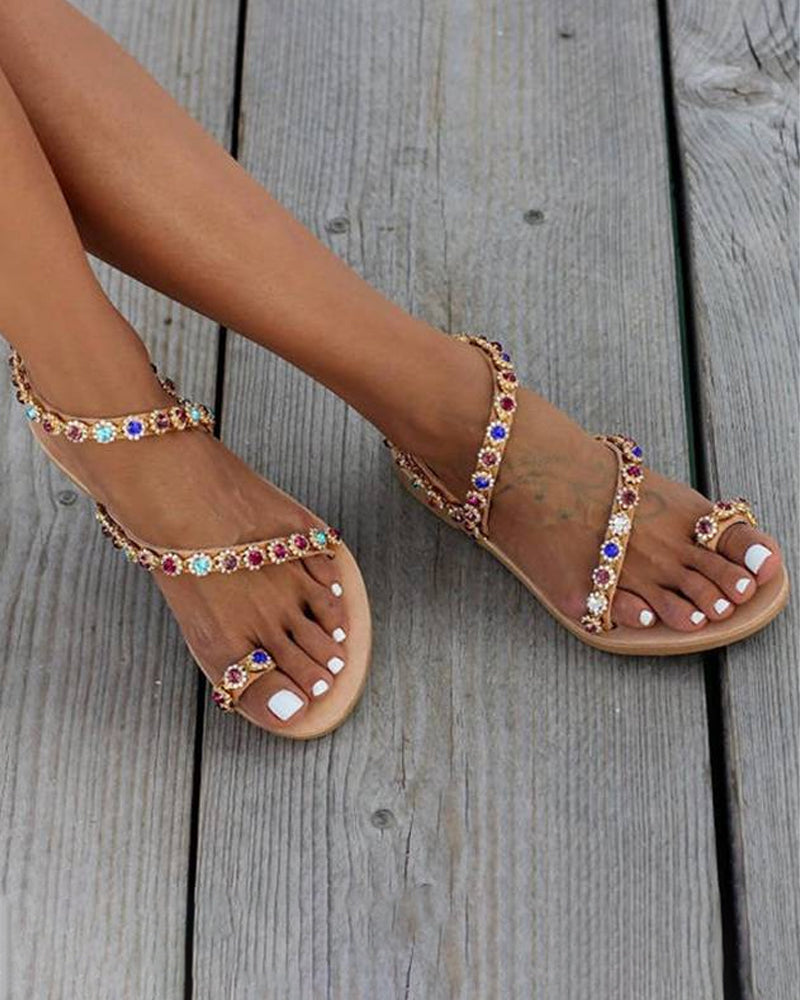 Gold-tone flat sandals with multicolor rhinestone straps and jeweled toe ring