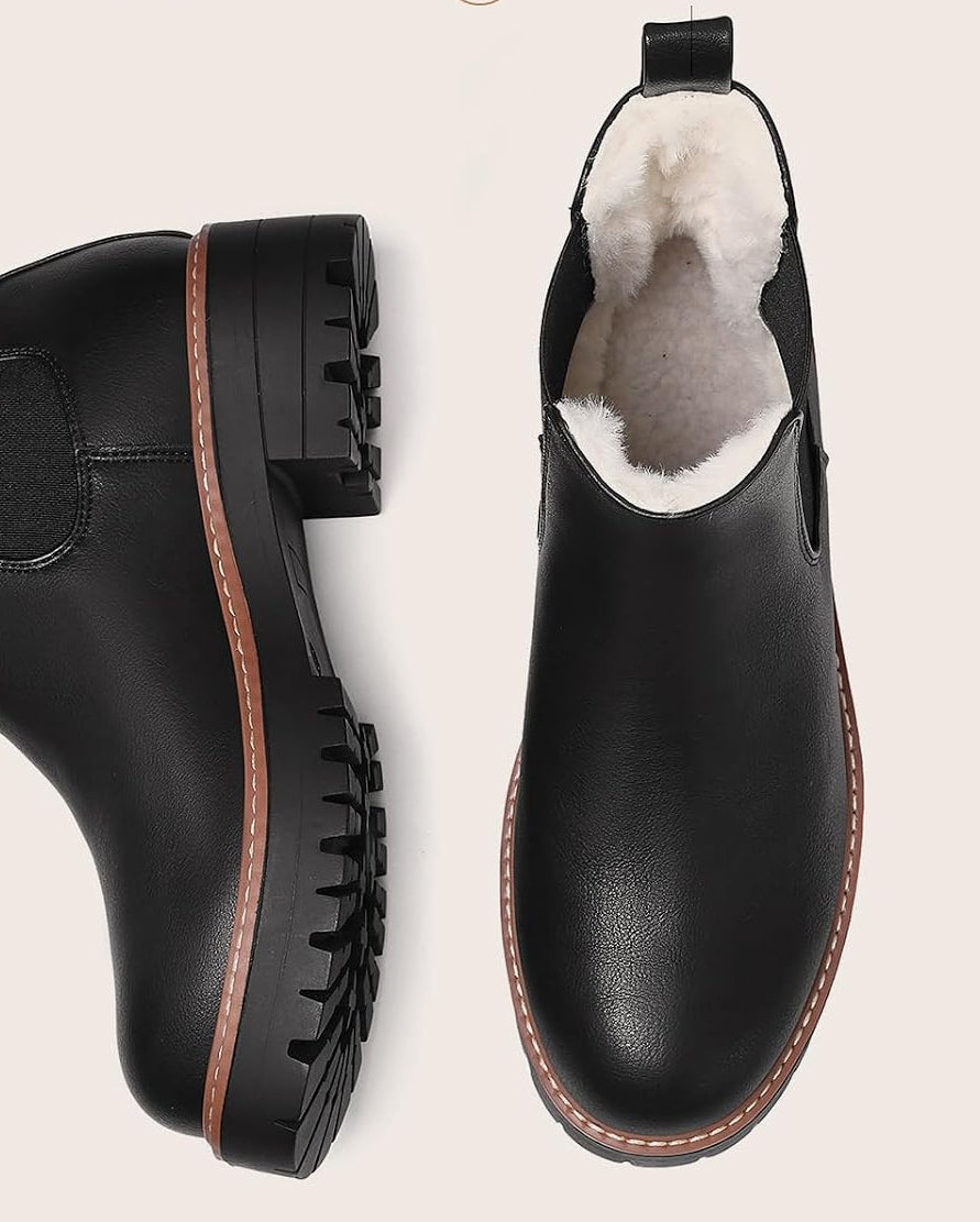 Black Chelsea boots showing the fur lining, rounded toes, and lug soles