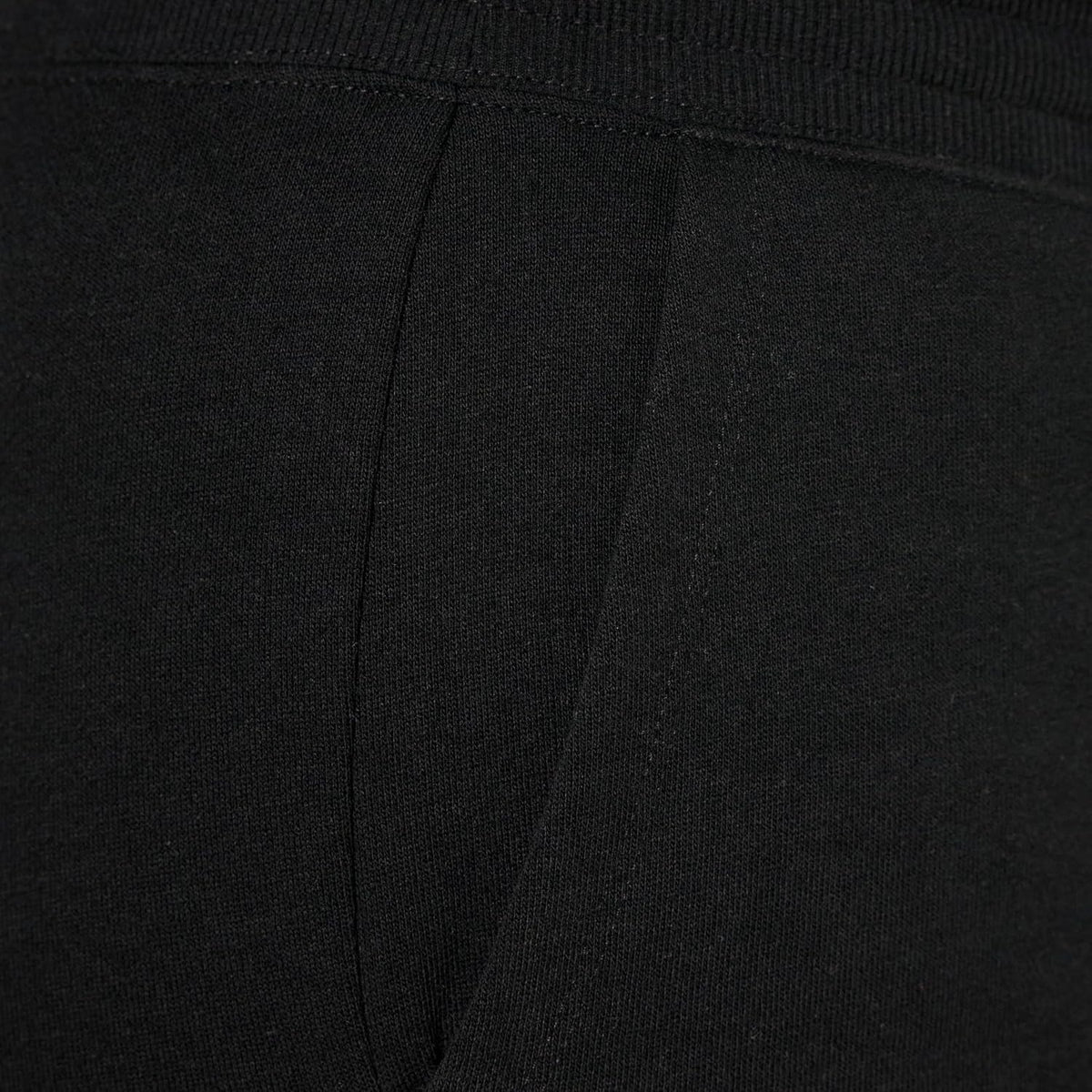 Women’s black fleece sweatpants fabric close-up with visible seams and waistband panel.