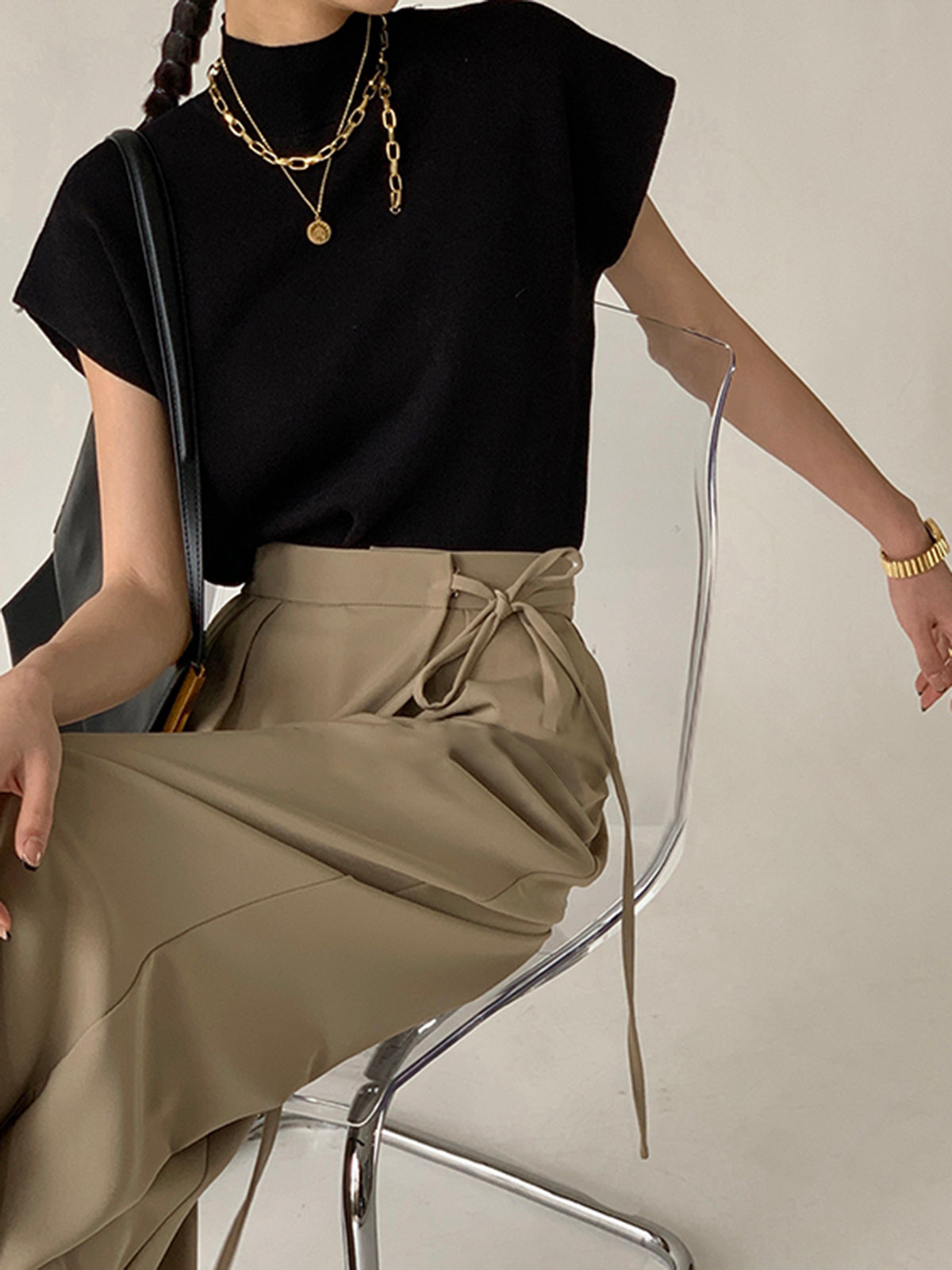 Black sleeveless mock neck knit top with draped neckline and short sleeves