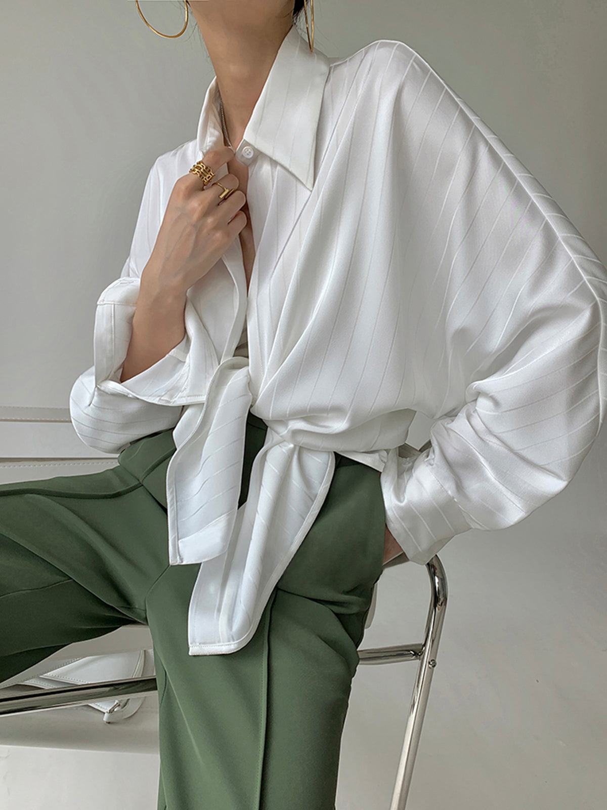 White satin oversized blouse with button-front collar, long sleeves, tied waist