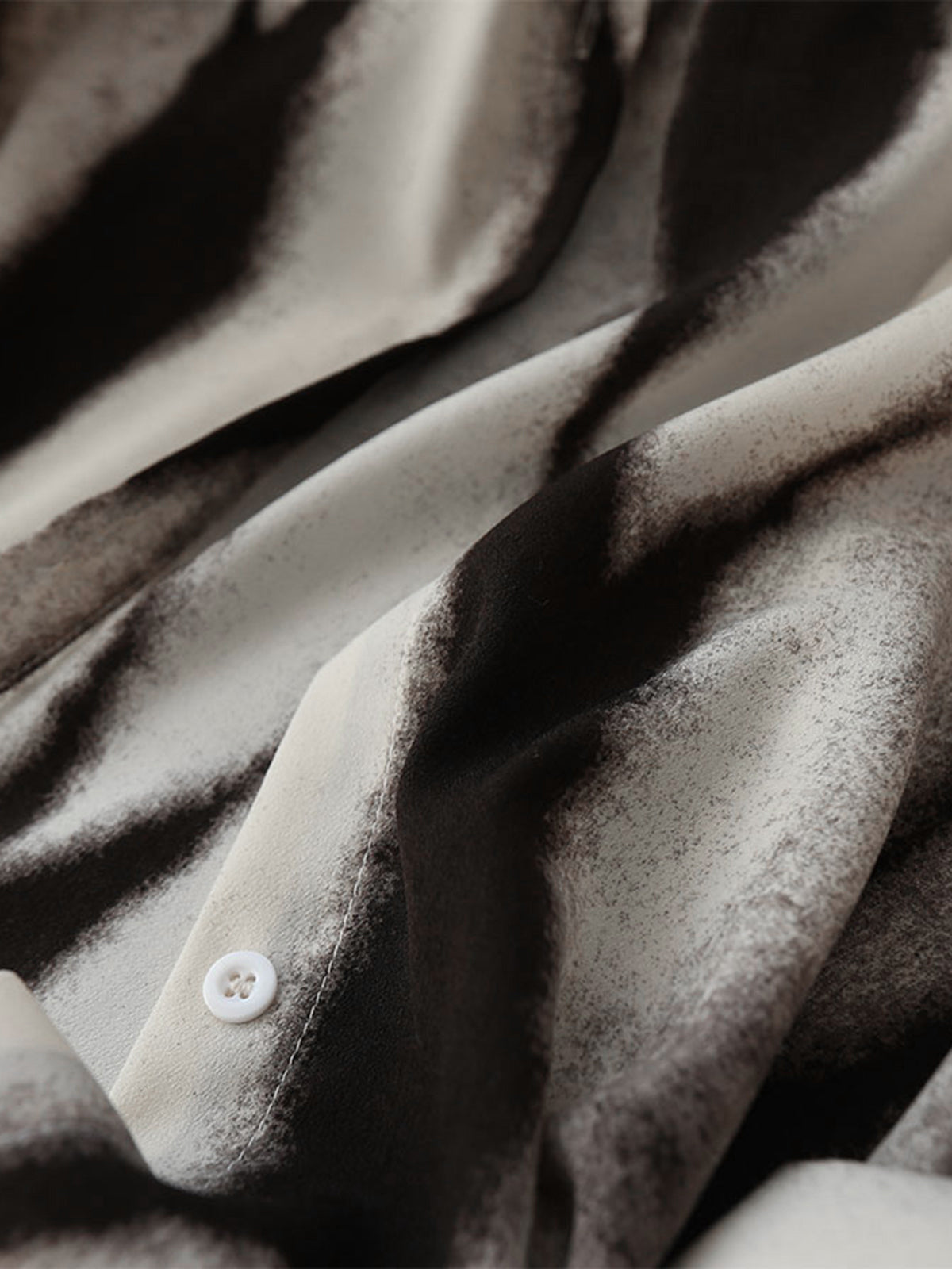 Close-up of abstract ink print satin blouse fabric with white button front