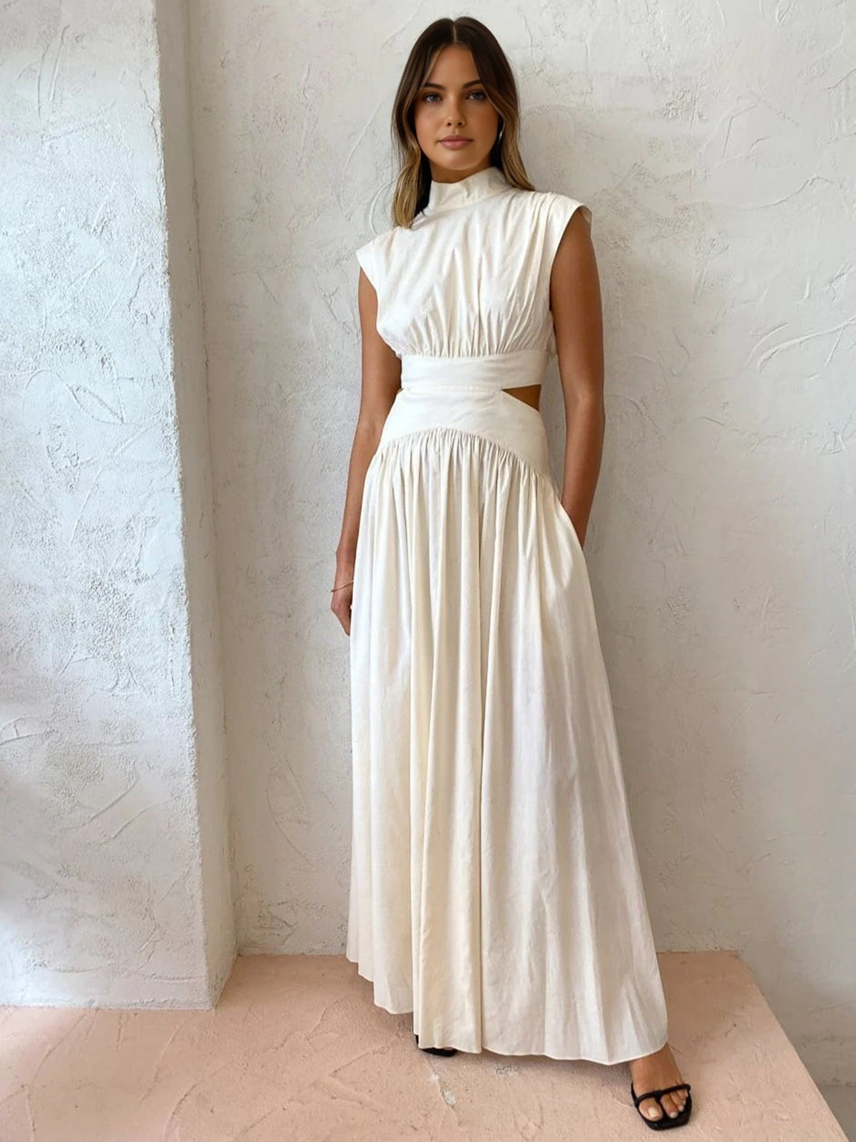 White sleeveless maxi dress with mock neck, ruched bodice, and full gathered skirt