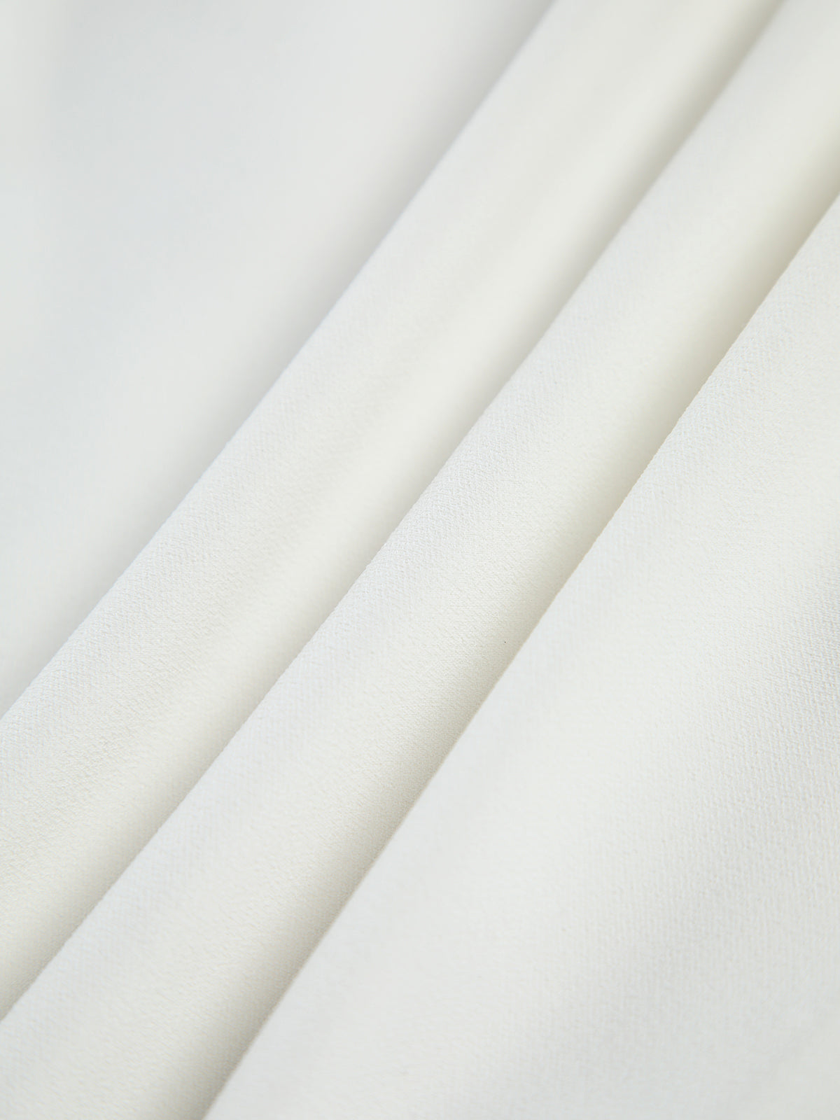 Off-white crepe fabric close-up showing fine texture and smooth drape