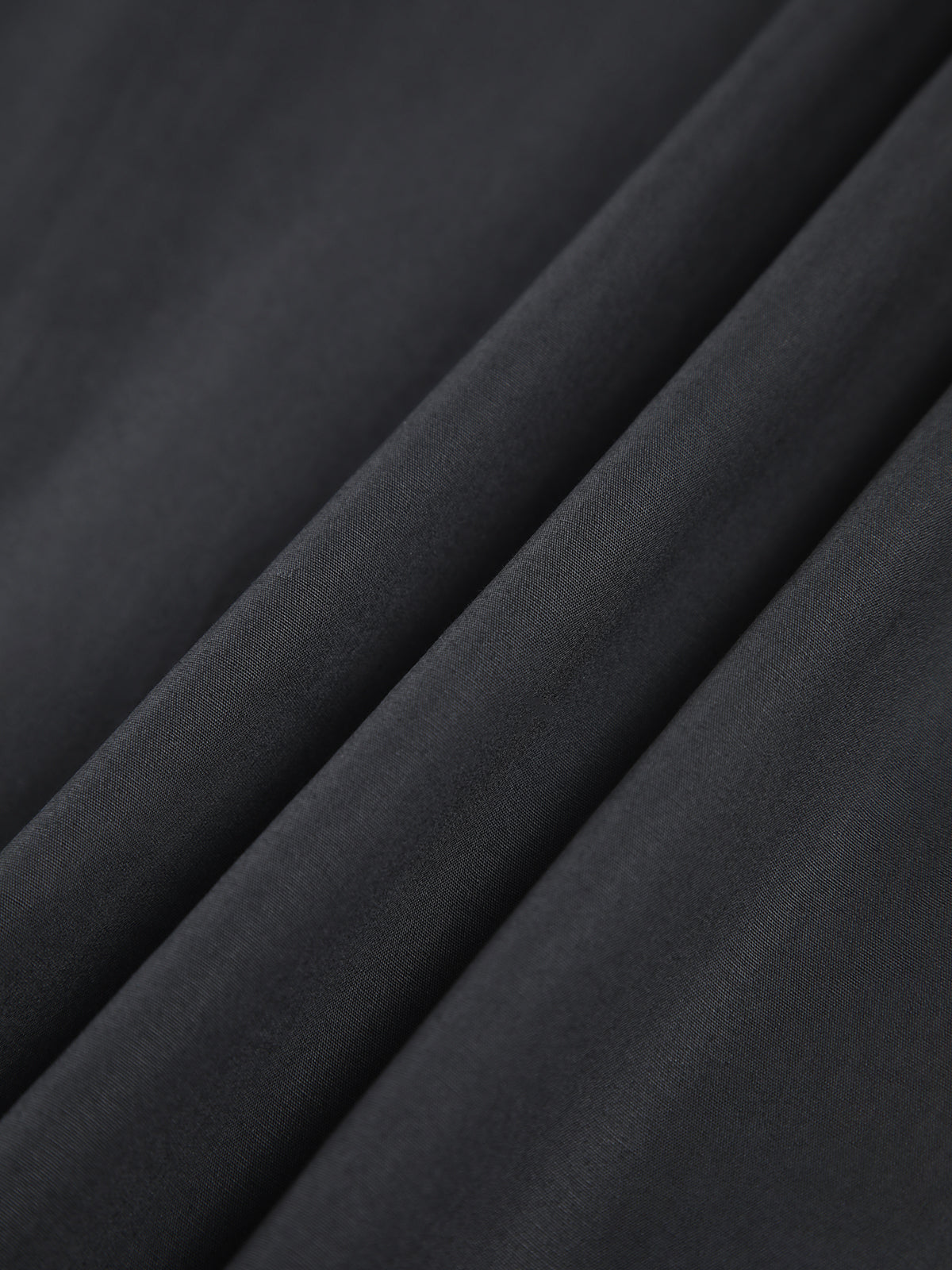 Black cotton fabric close-up showing ribbed texture and soft woven finish