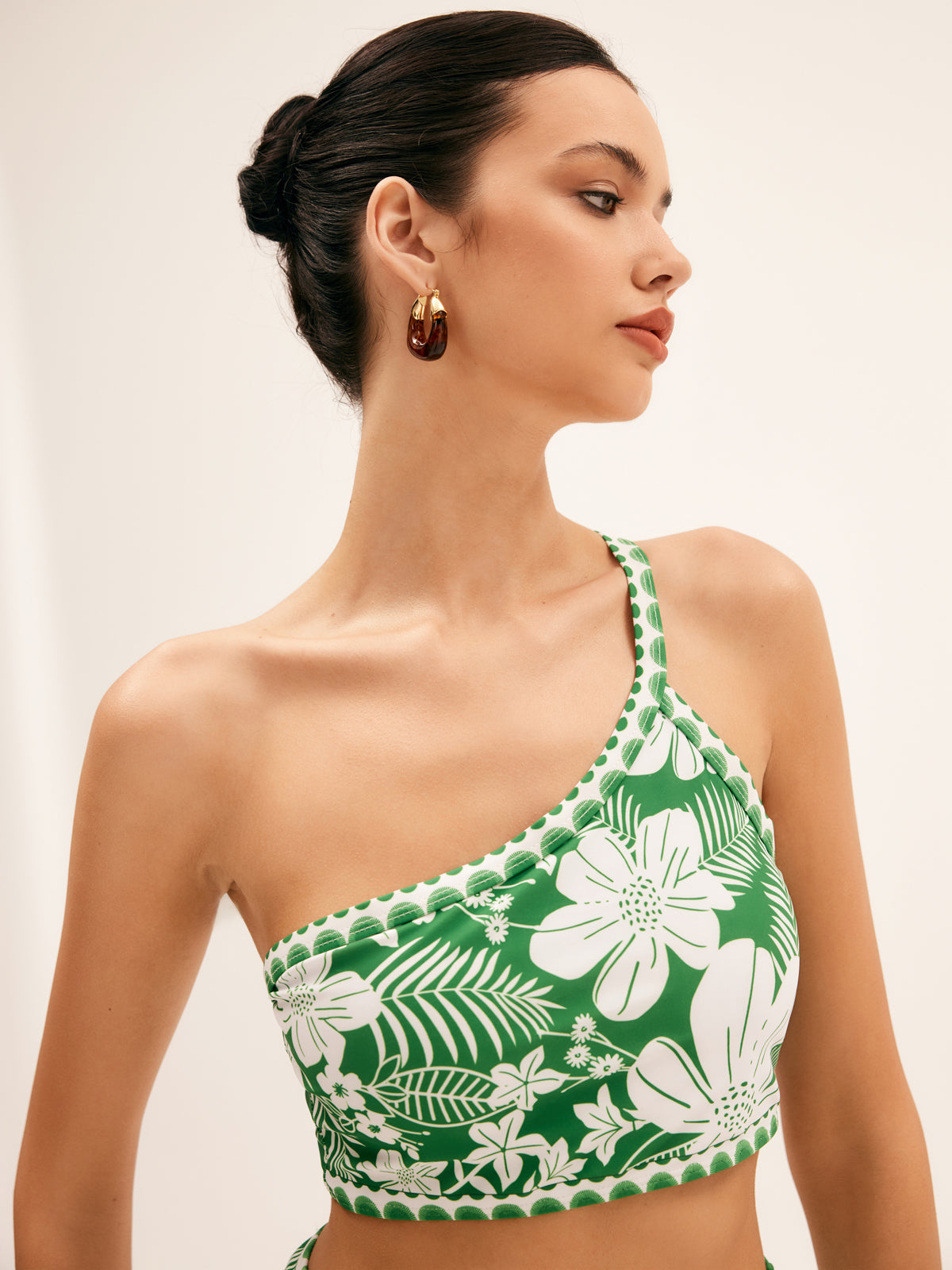 Green one-shoulder bikini top with tropical floral print, close-up.