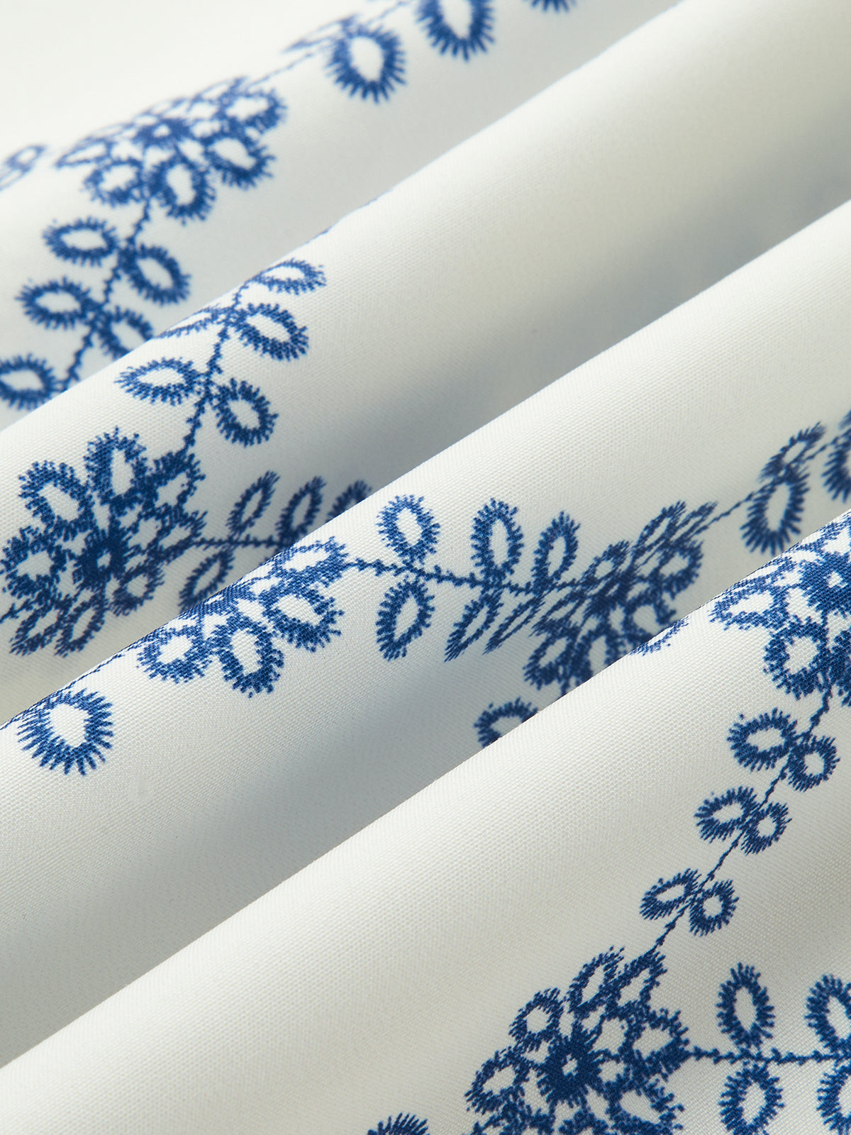 Blue embroidered floral pattern on white linen fabric