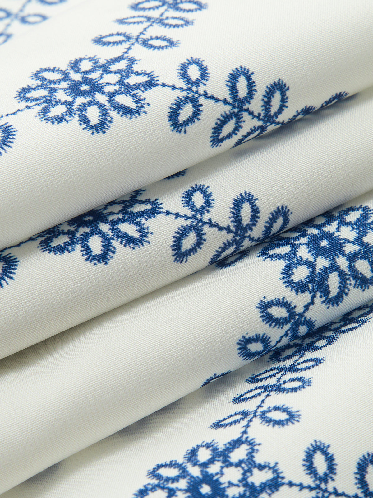 Blue embroidered flower motifs on white linen fabric roll