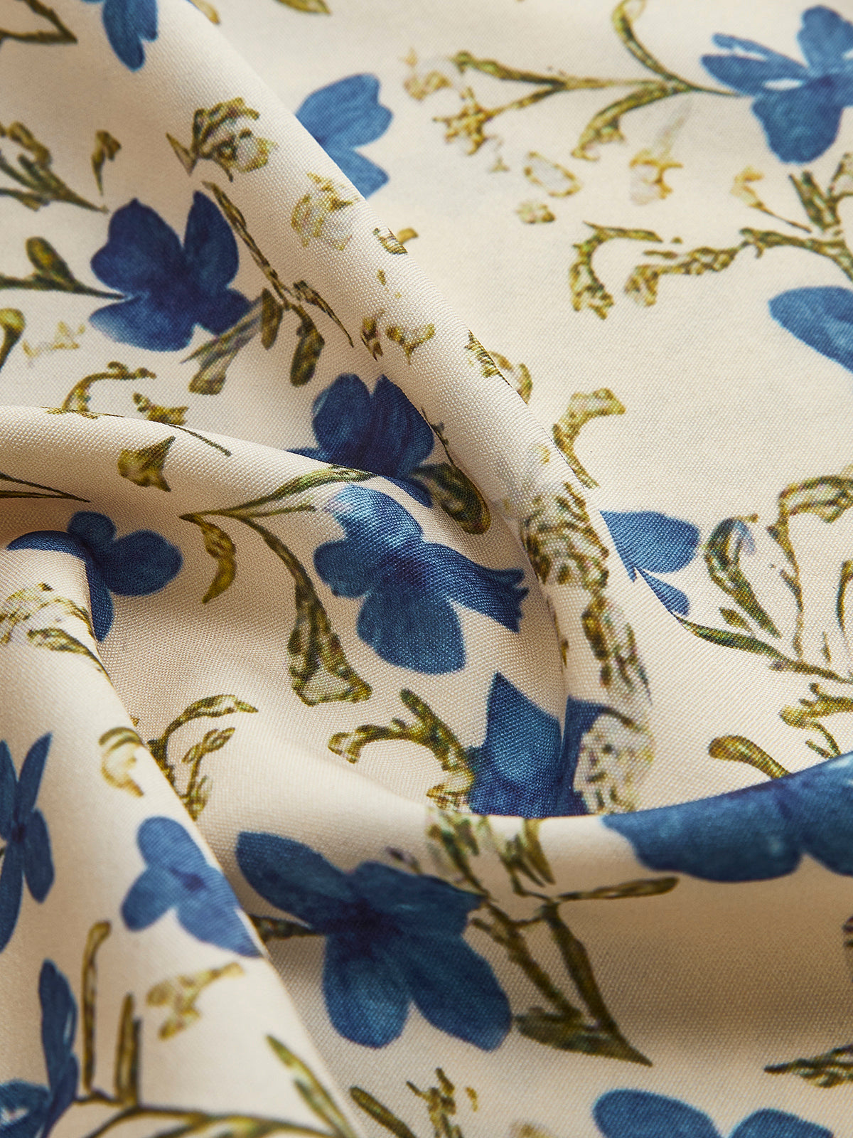 Close-up of blue and navy floral print chiffon fabric on light base