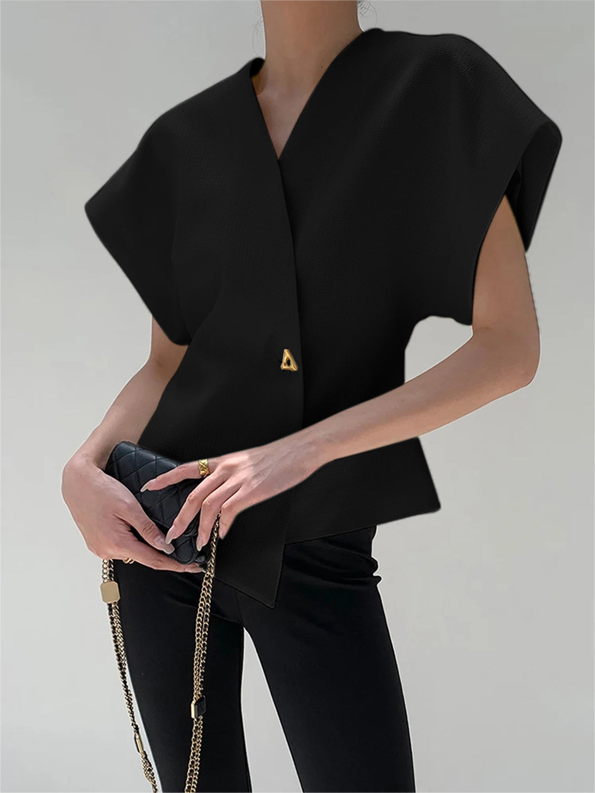 Black crepe blouse with V-neck, cap sleeves, and an asymmetric gold button detail