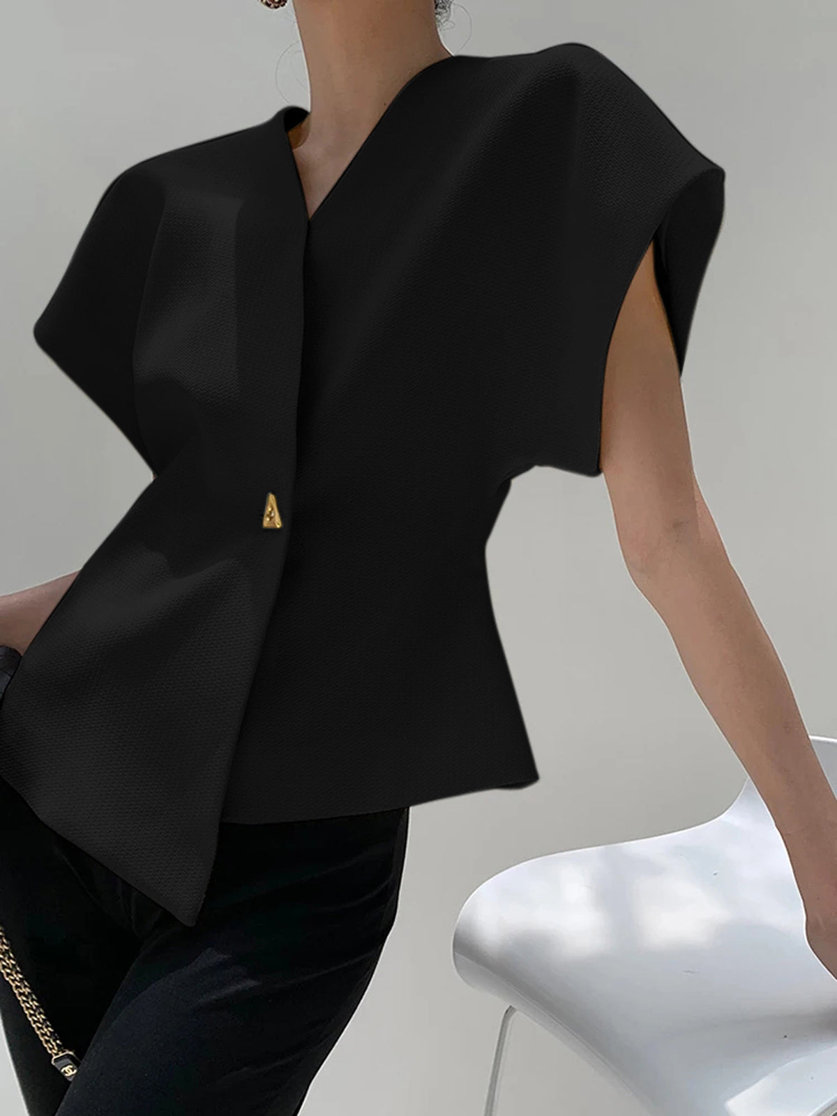 Black crepe blouse with V-neck, cap sleeves, and asymmetric gold button detail