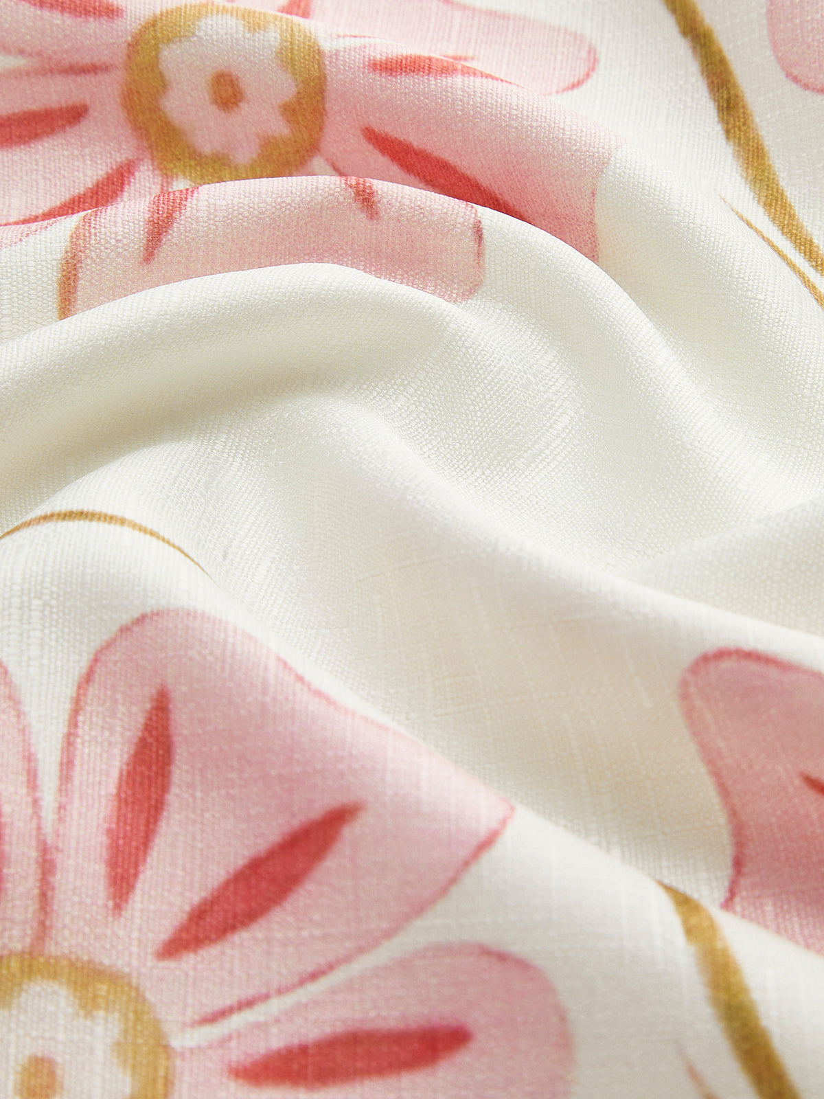 White linen fabric detail with pink flower petals and gold vine lines