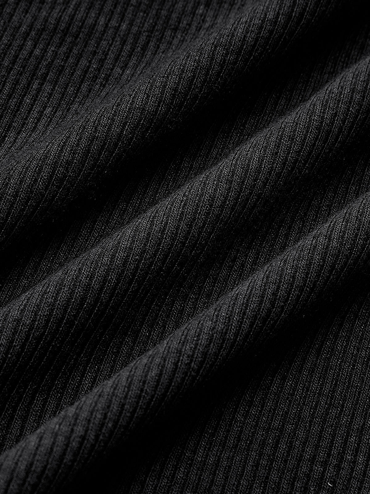 Close-up of black ribbed knit fabric with fine vertical ridges and gentle drape folds