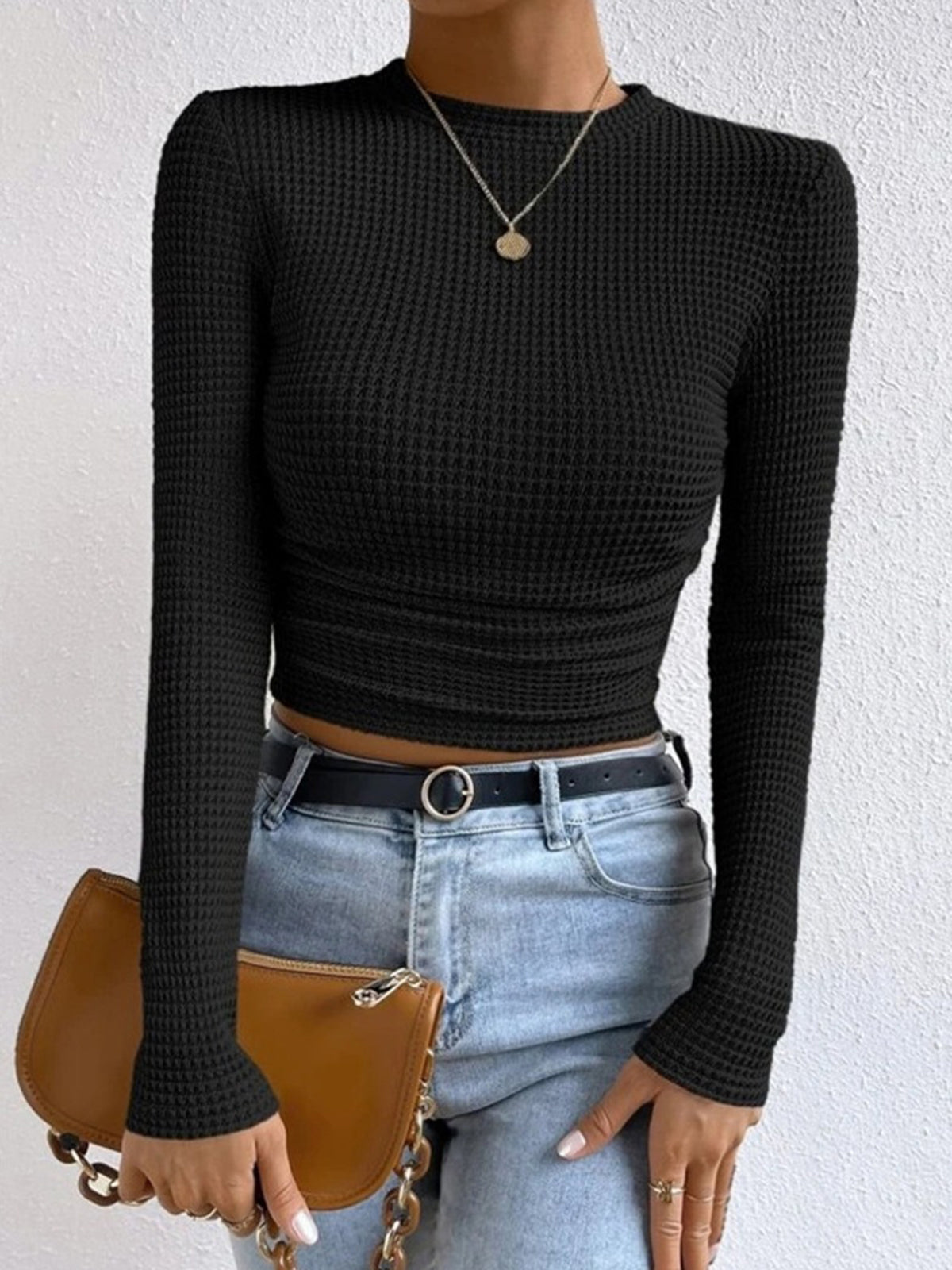 Black waffle-knit long-sleeve slim crop top with ruched waist and fitted silhouette.