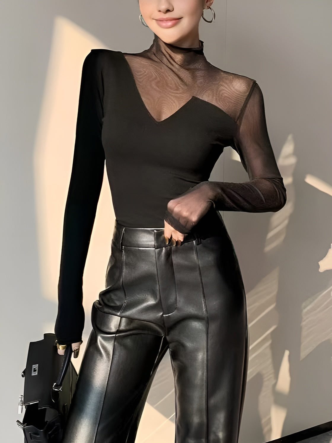 Black fitted mesh top with mock neck, sheer long sleeves, and asymmetric chest insert