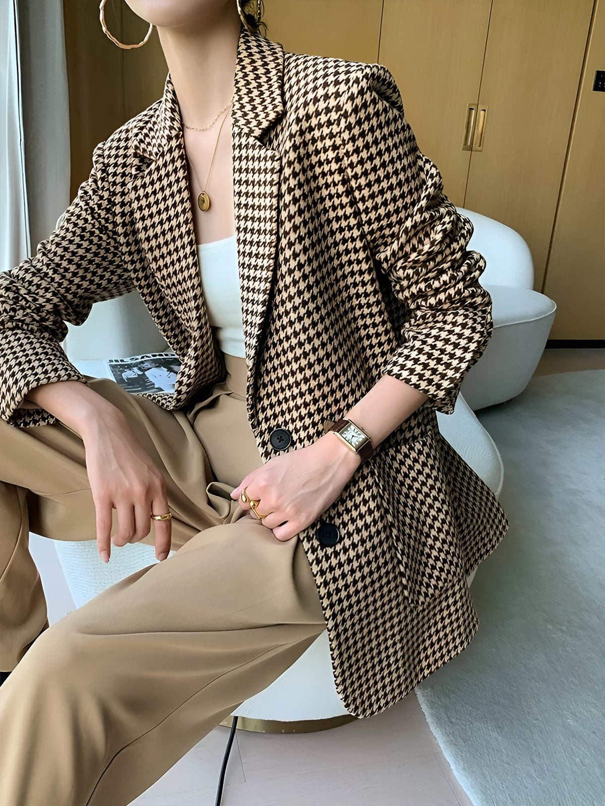 Women's houndstooth blazer with notch lapel and brown belt at waist, seated detail
