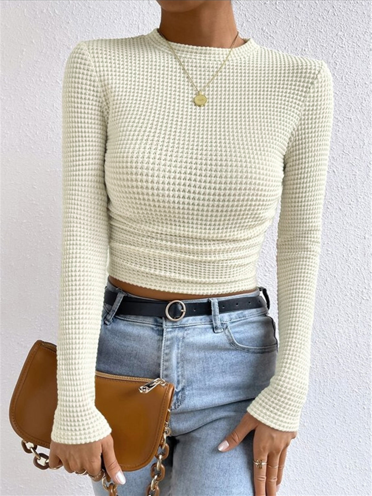 Light cream waffle-knit long-sleeve slim crop top with ruched hem and crew neckline.
