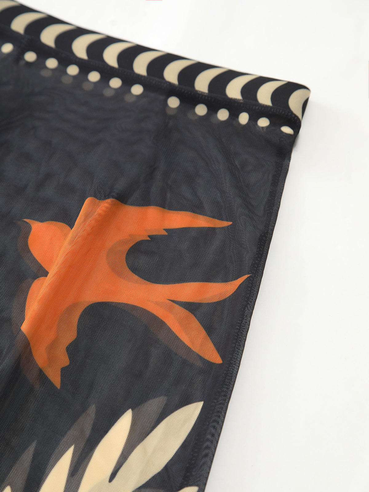 Chiffon fabric swatch with dark base and orange tropical leaf motif