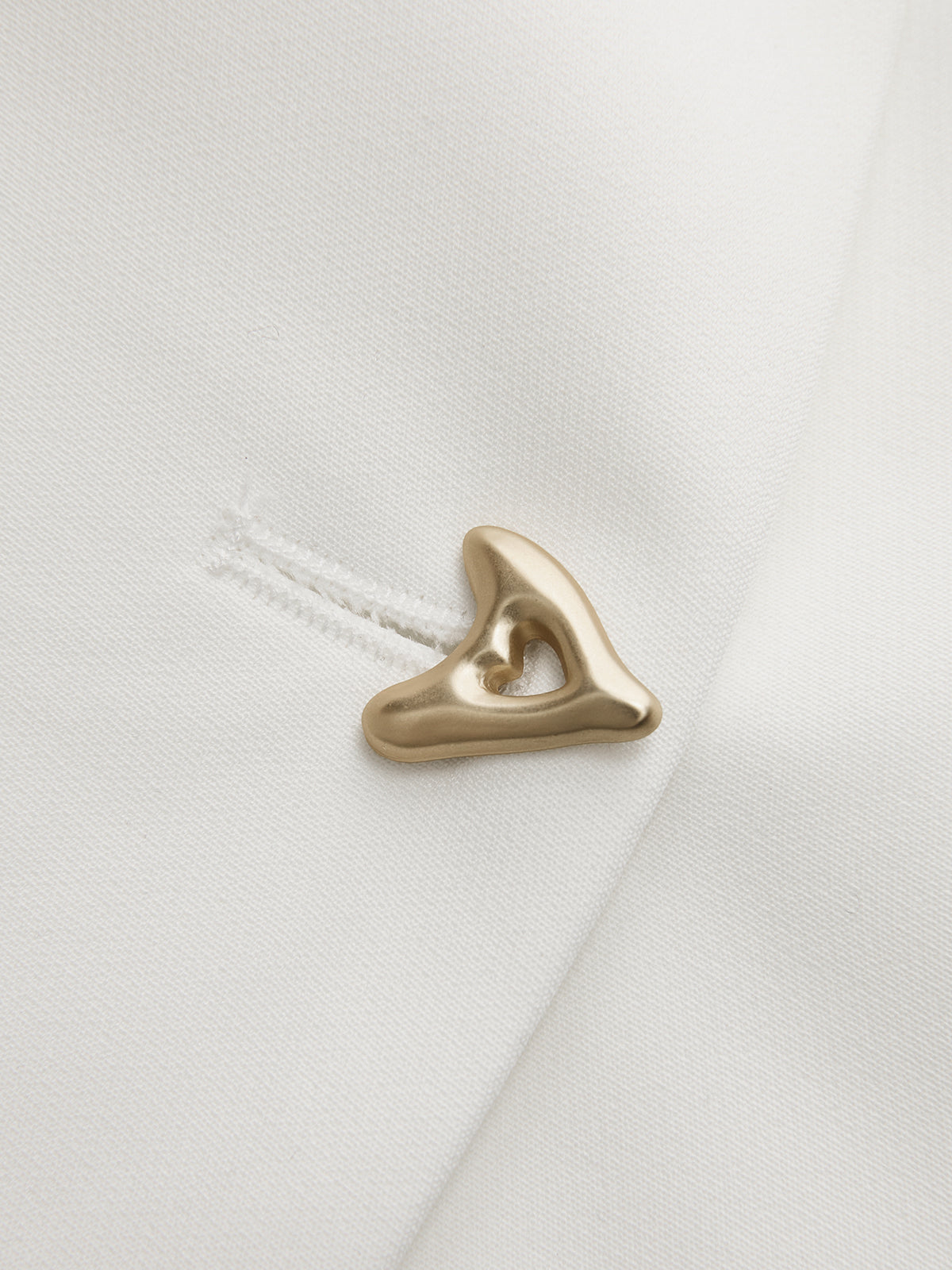 Gold asymmetric button detail on white crepe blouse, shaped metal shank
