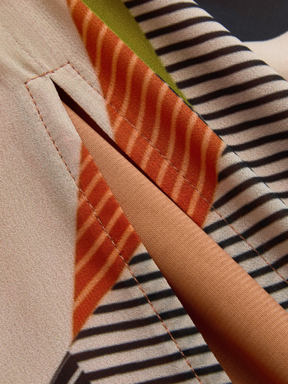 Multicolor striped dress fabric close-up, stitched seam and angled panel details