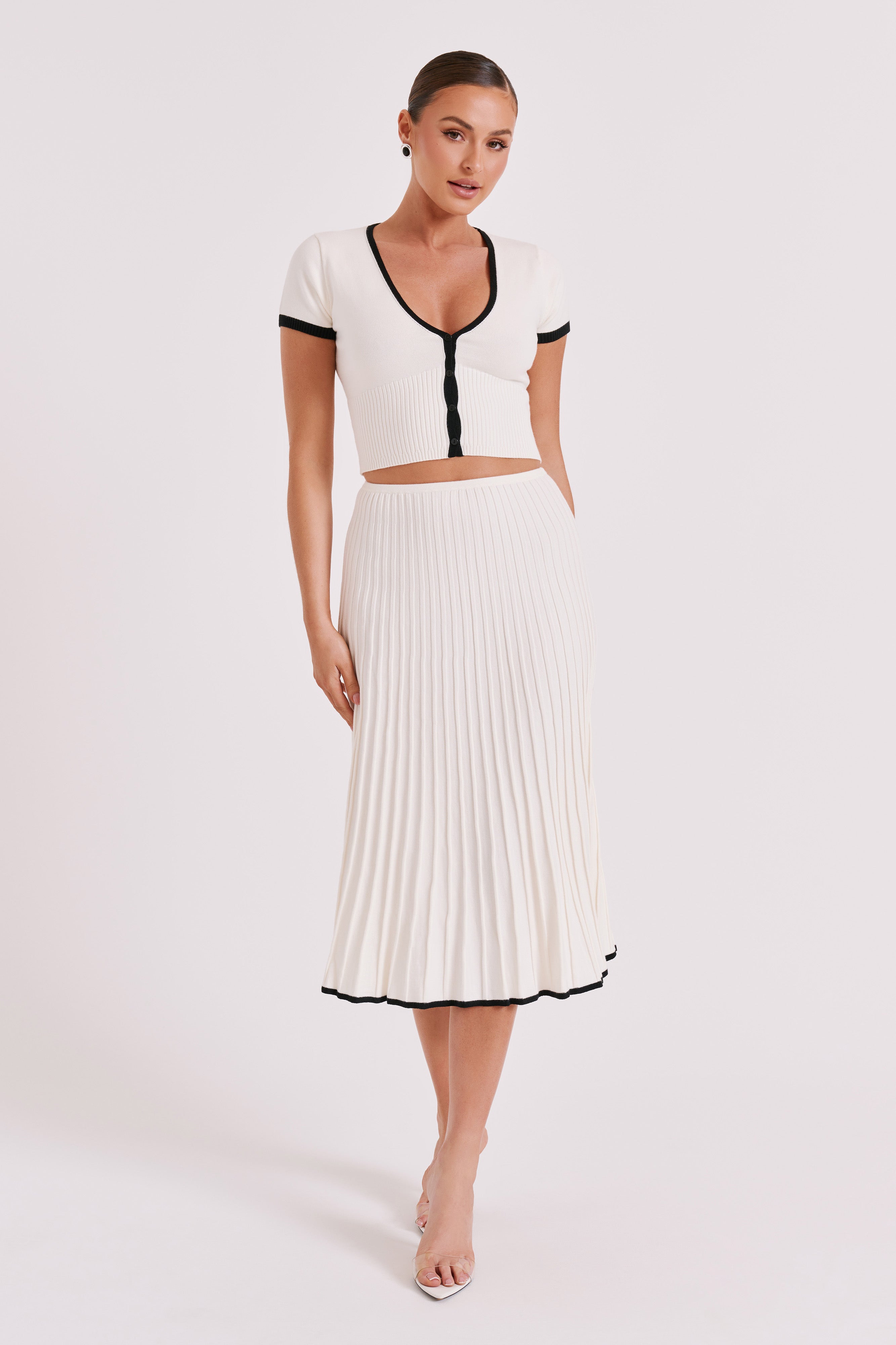 Full view of white ribbed crop top and pleated midi skirt set with black-trim accents.