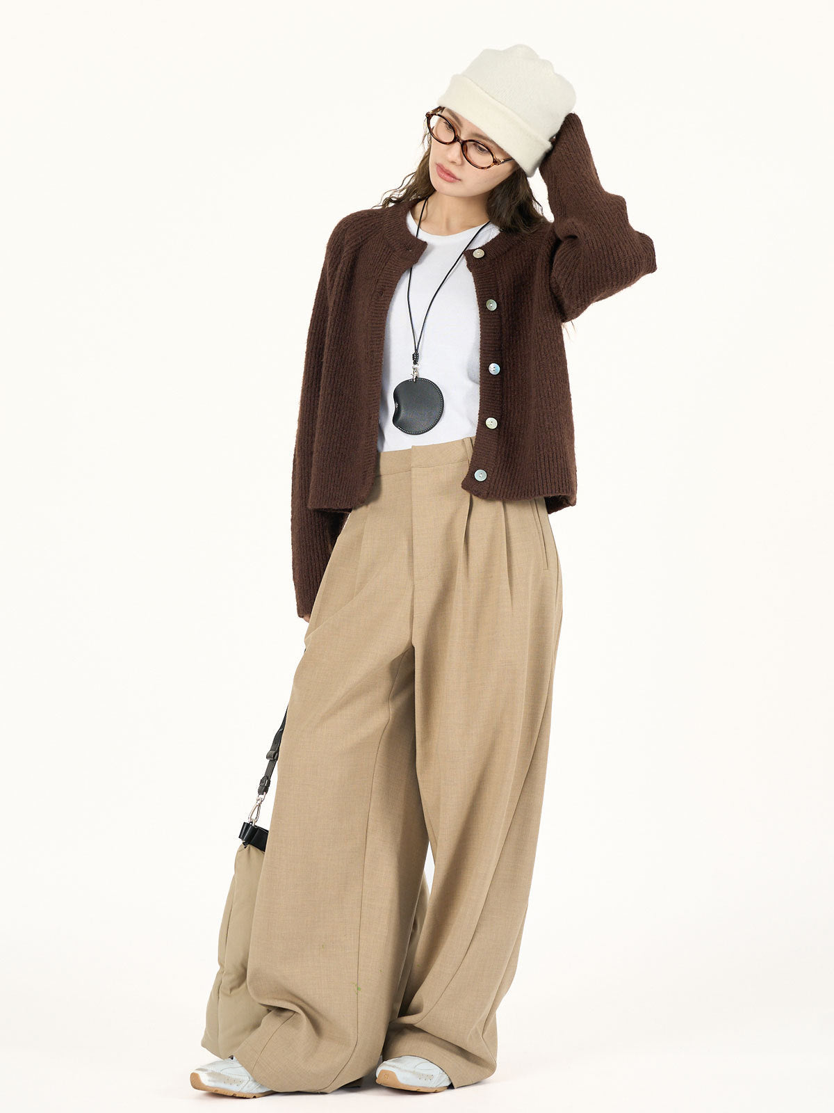 Brown button-front knitted cardigan worn open over a white top