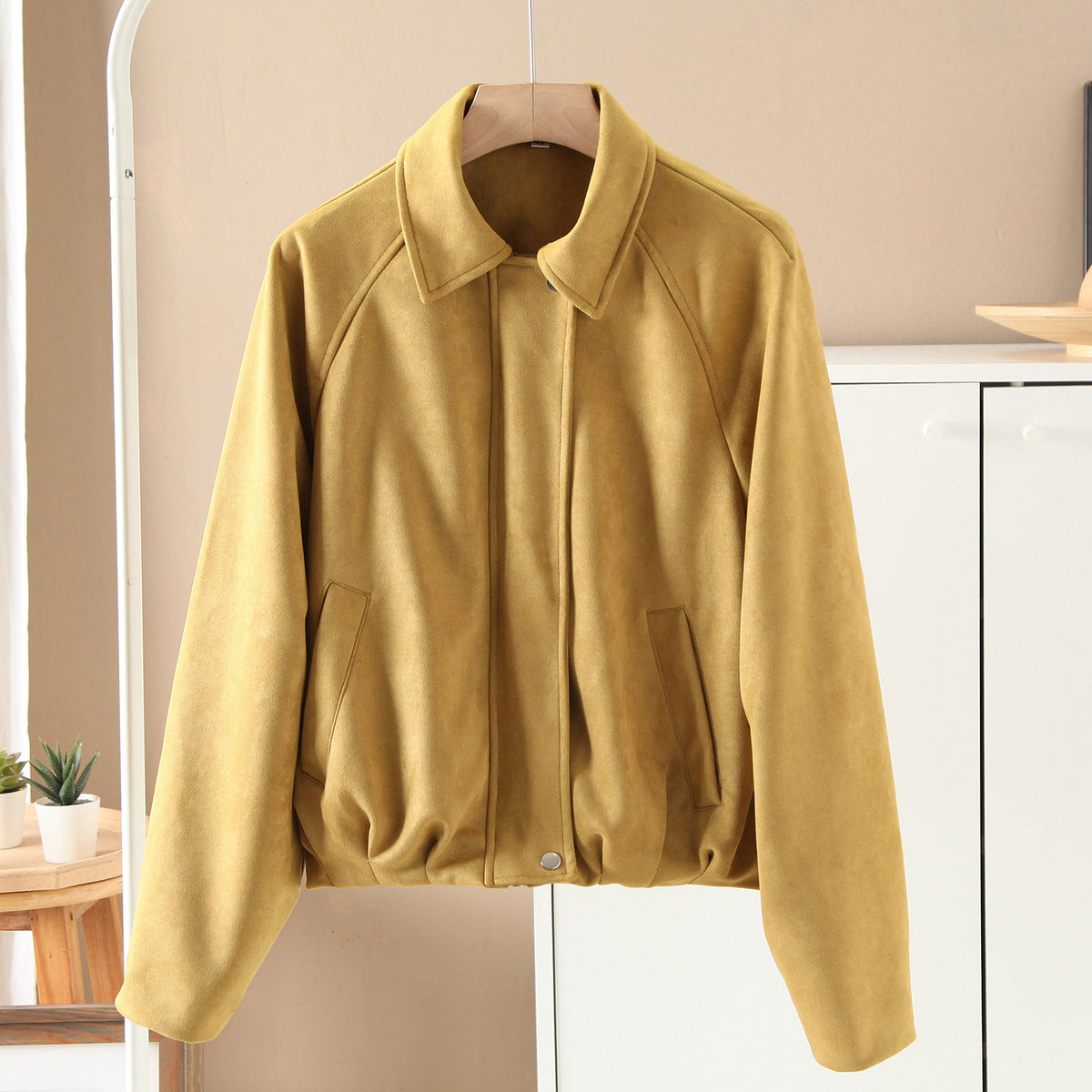 Yellow faux suede bomber jacket with stand collar, front button closure, and contrast topstitching