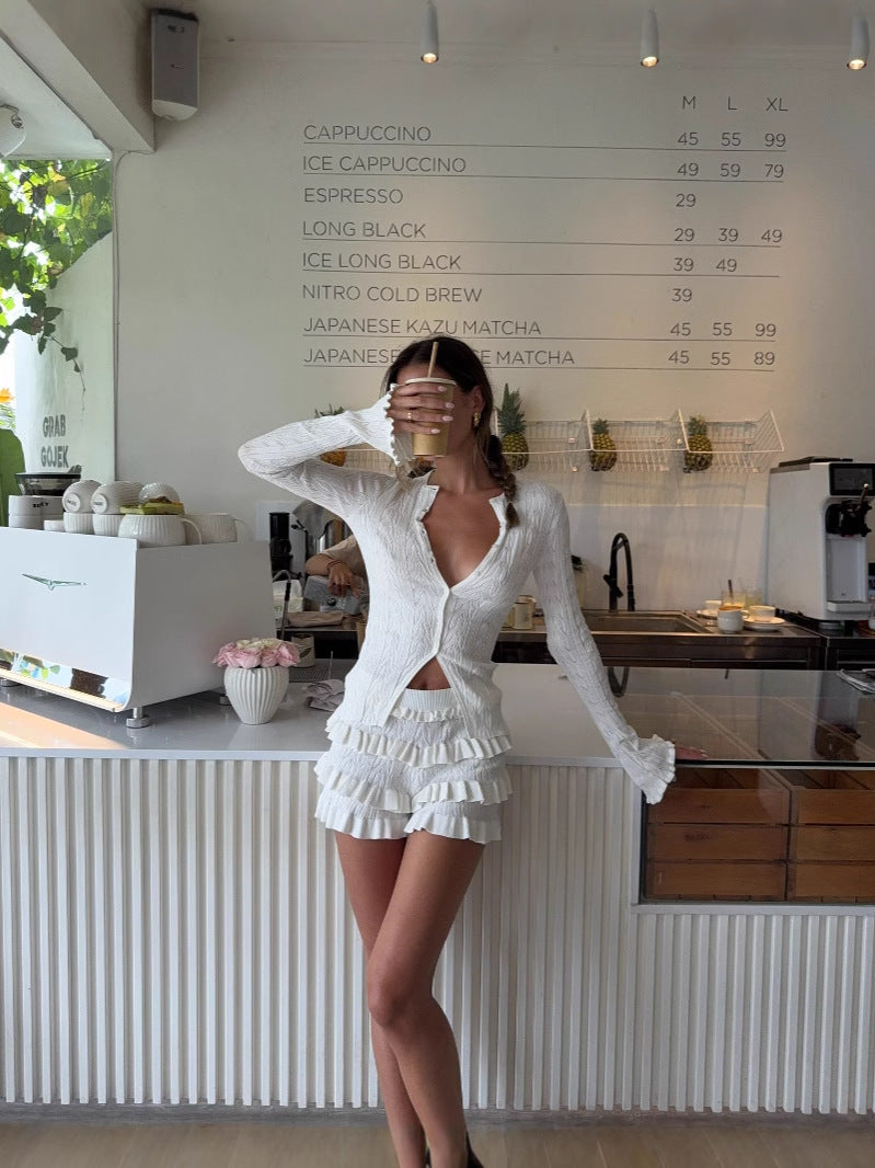 White knitted long-sleeve cardigan with tiered ruffle hem, standing pose