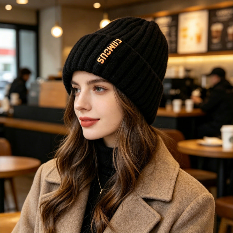 Black ribbed knit beanie with folded cuff and branded patch on the side