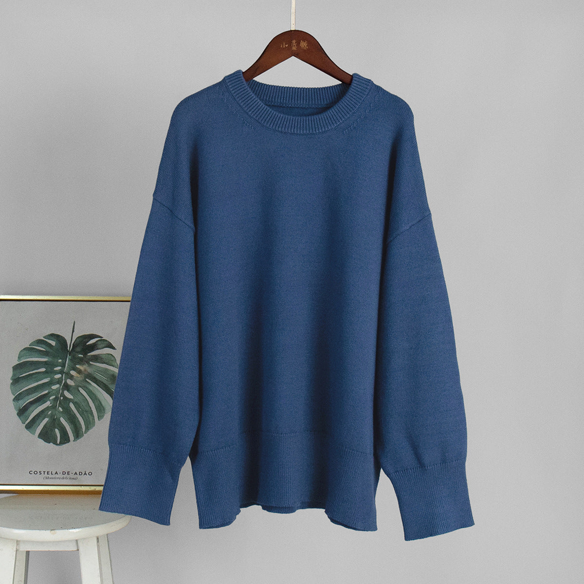 Blue round-neck knit sweater on a hanger with ribbed collar and cuffs
