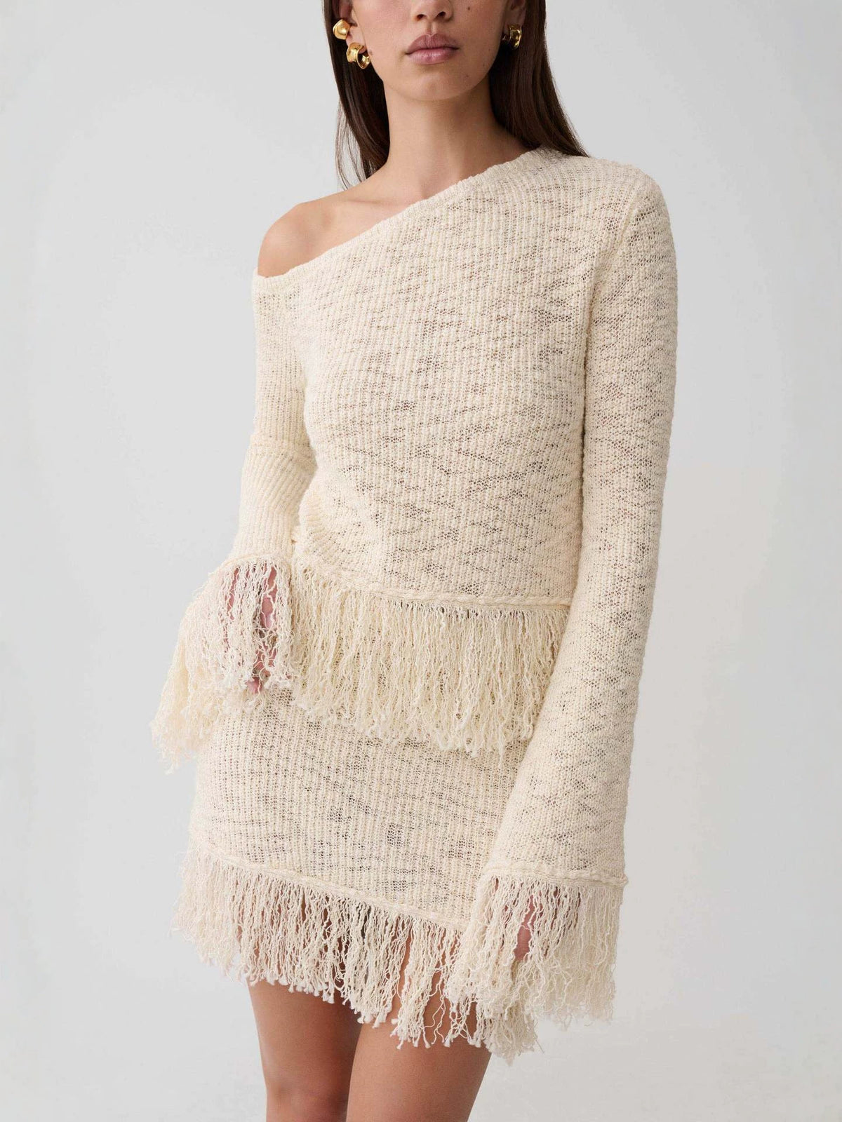 Apricot hollow-knit off-shoulder sweater top with long sleeves and layered fringe detail near hem