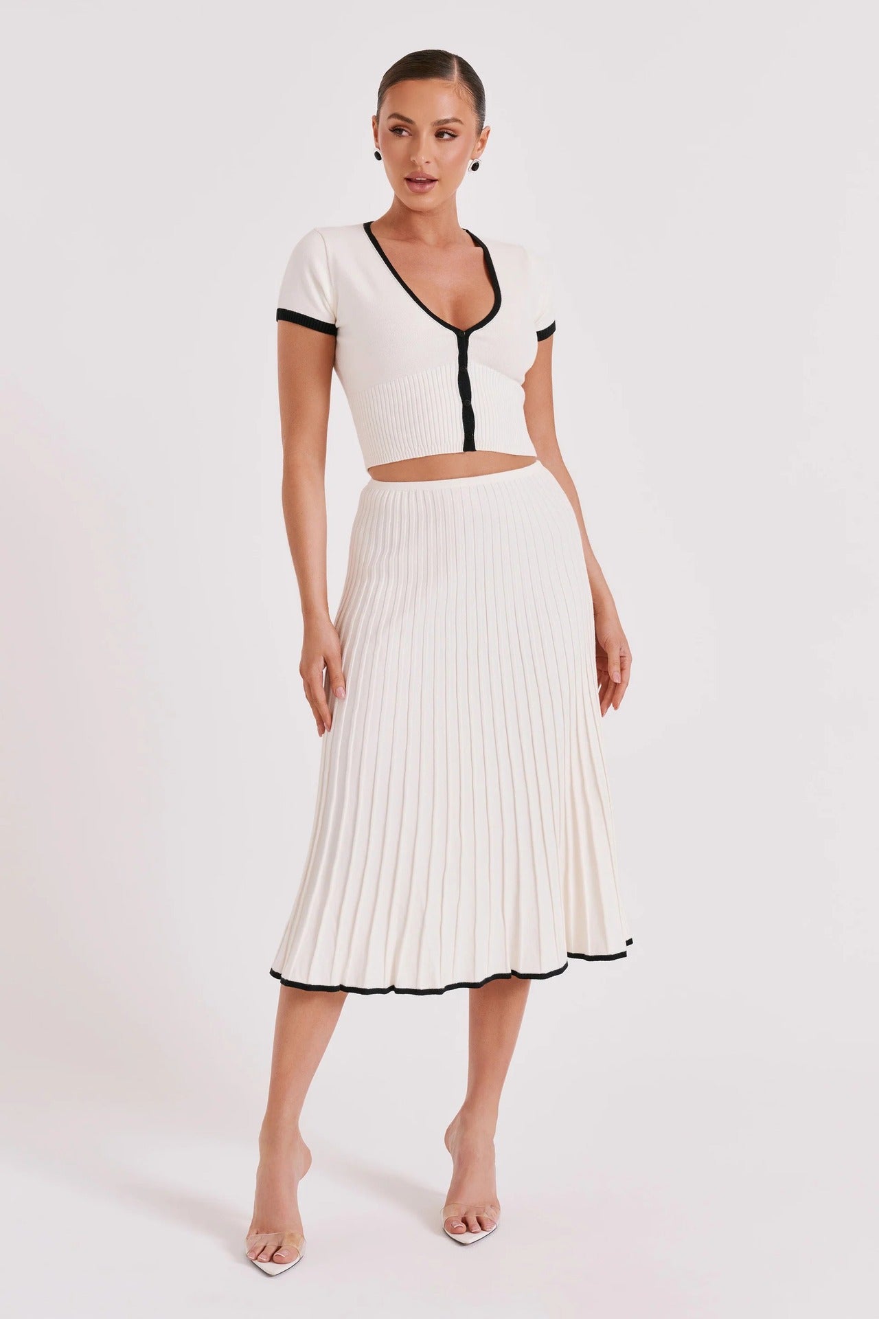 White knit two-piece set with cropped top and pleated midi skirt, black trim