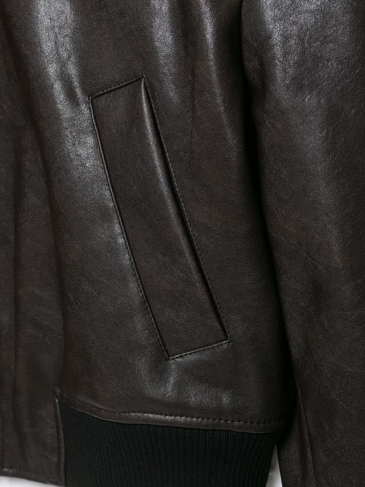 Close-up of a slanted welt pocket and ribbed hem on the leather-effect jacket