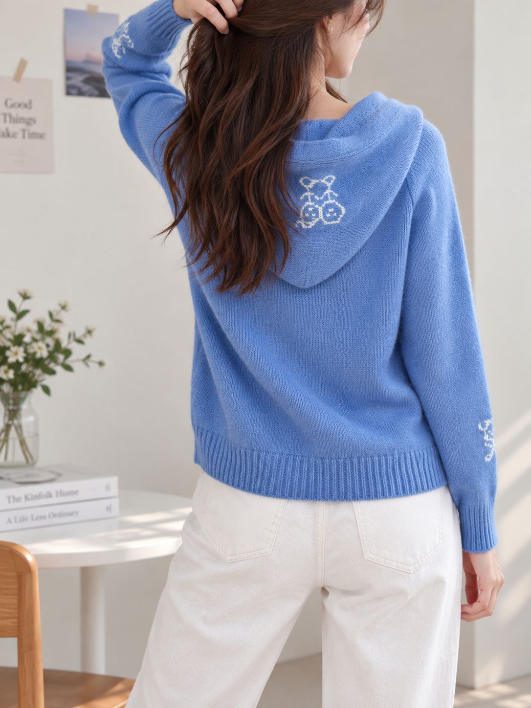 Blue knit hooded cardigan with graphic emblem on back and ribbed cuffs.