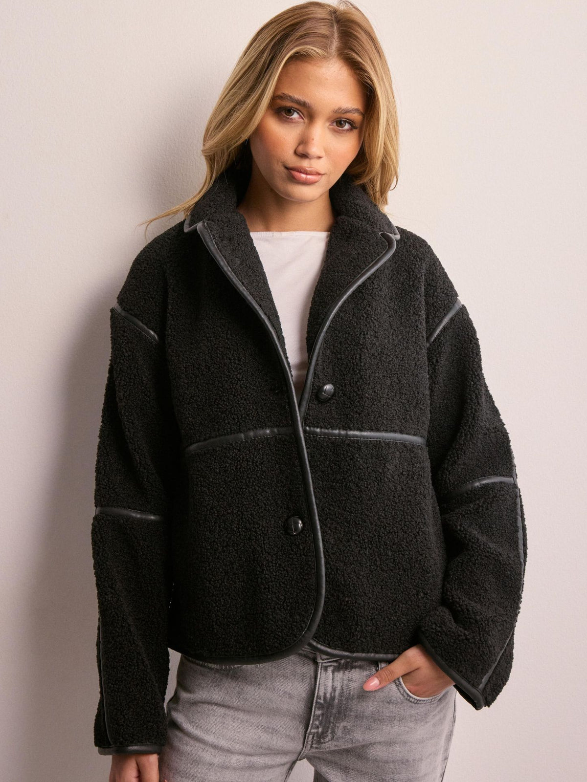 Black fleece jacket with notched lapels, contrast piping, and button closure