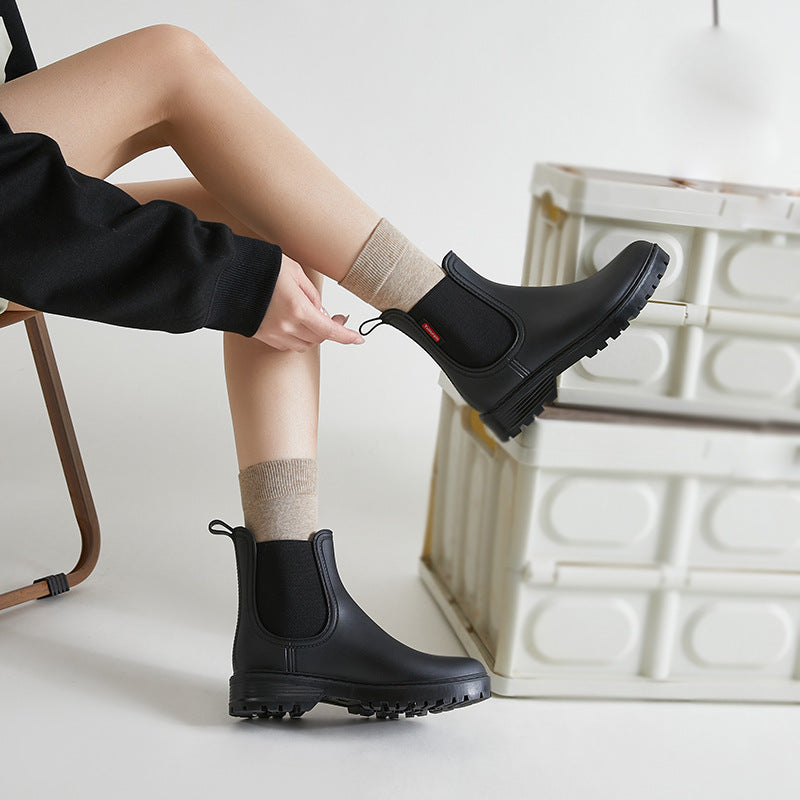 Black short-tube Chelsea rain boots with elastic side panels and thick tread sole