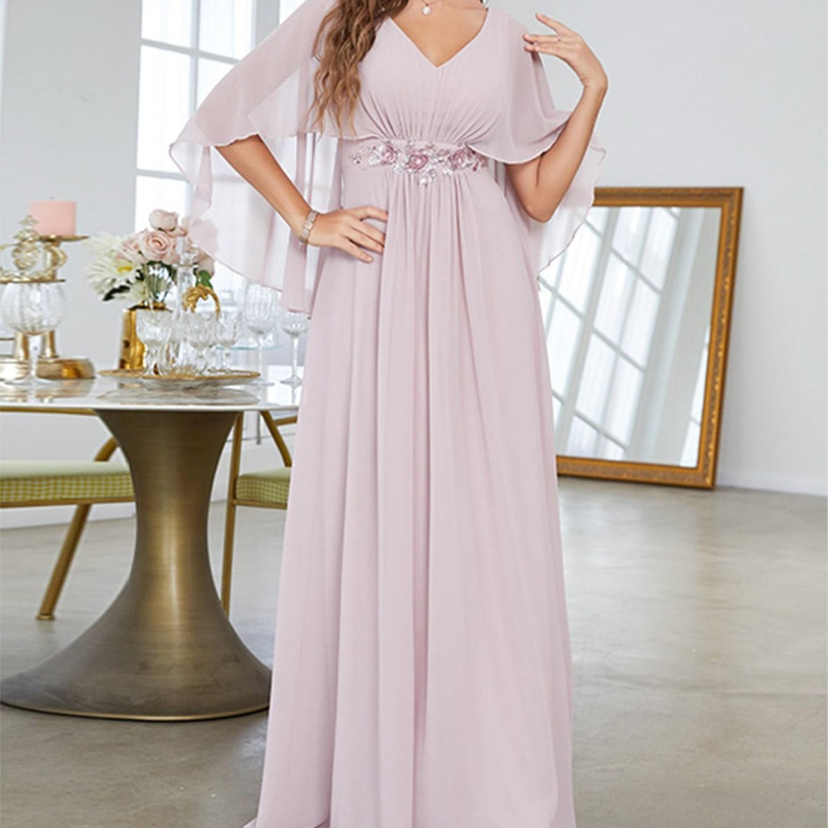 Light pink V-neck evening gown with cape sleeves, embroidered belt and flowing skirt