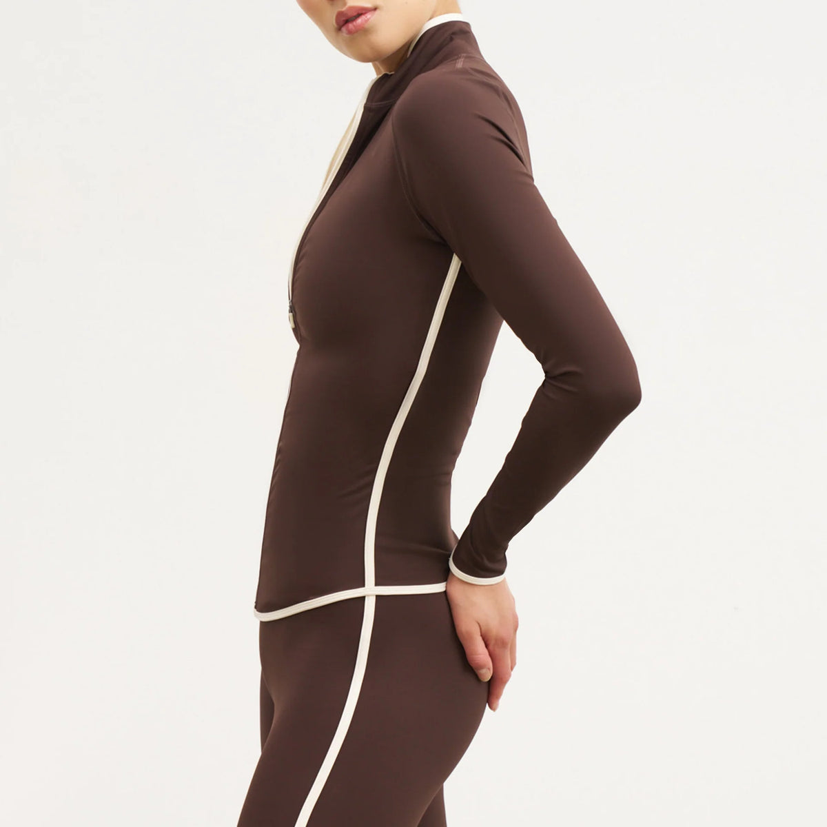Brown fitted yoga jacket with white piping, shown from the side