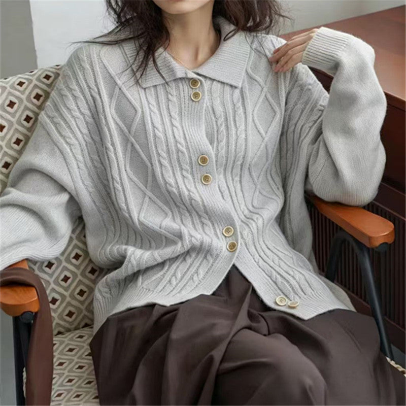 Light gray cable-knit cardigan with pointed collar and buttons, shown seated