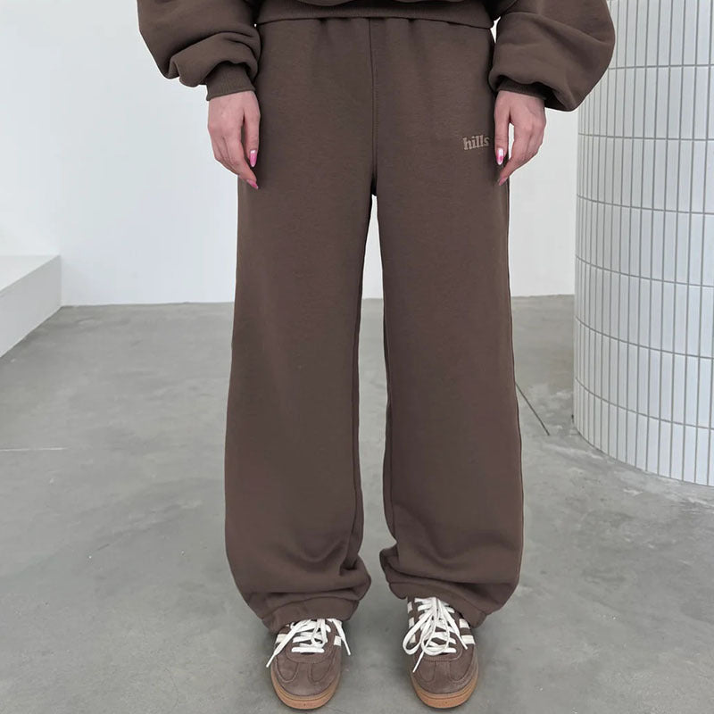 Dark brown sweatpants with elastic waistband, relaxed fit, and small right-leg text