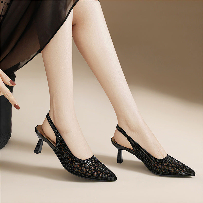 Black pointed-toe slingback heels with geometric cutout upper and thin heel on feet.