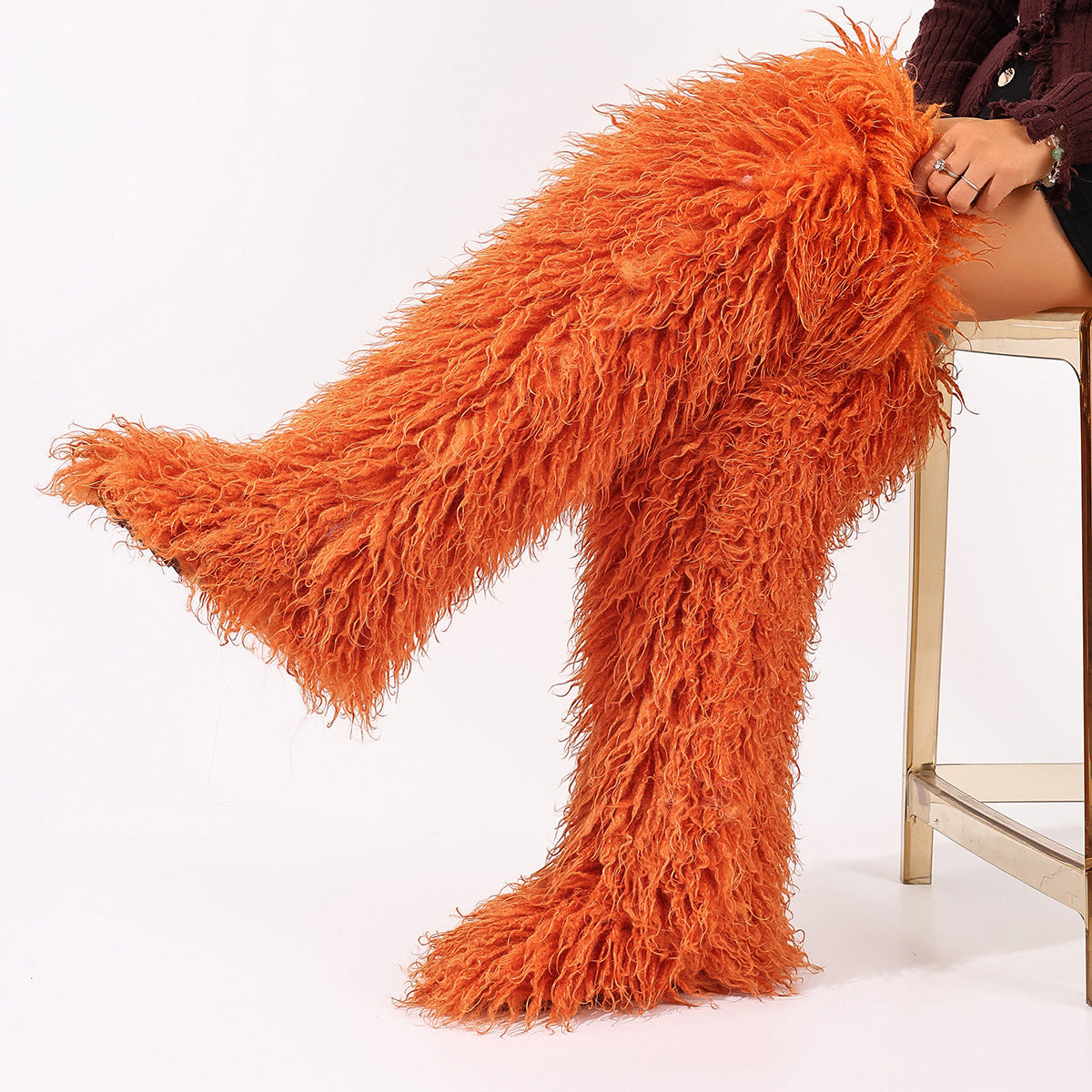 Orange faux-fur thigh-high boots with long pile, shown worn with one leg raised.