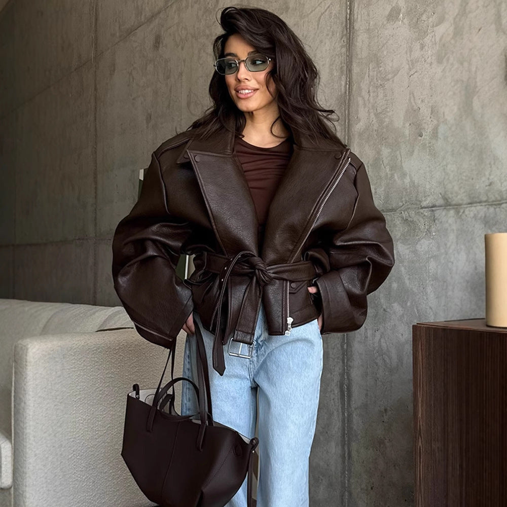 Women's brown short leather motorcycle jacket with lapel, zip, and tied waist belt