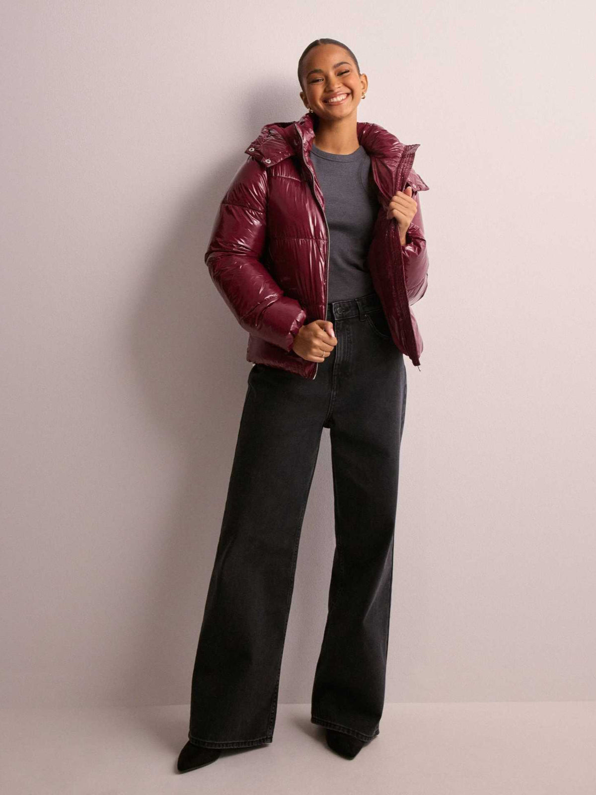 Shiny burgundy puffer jacket with oversized hood and front zipper, quilted finish