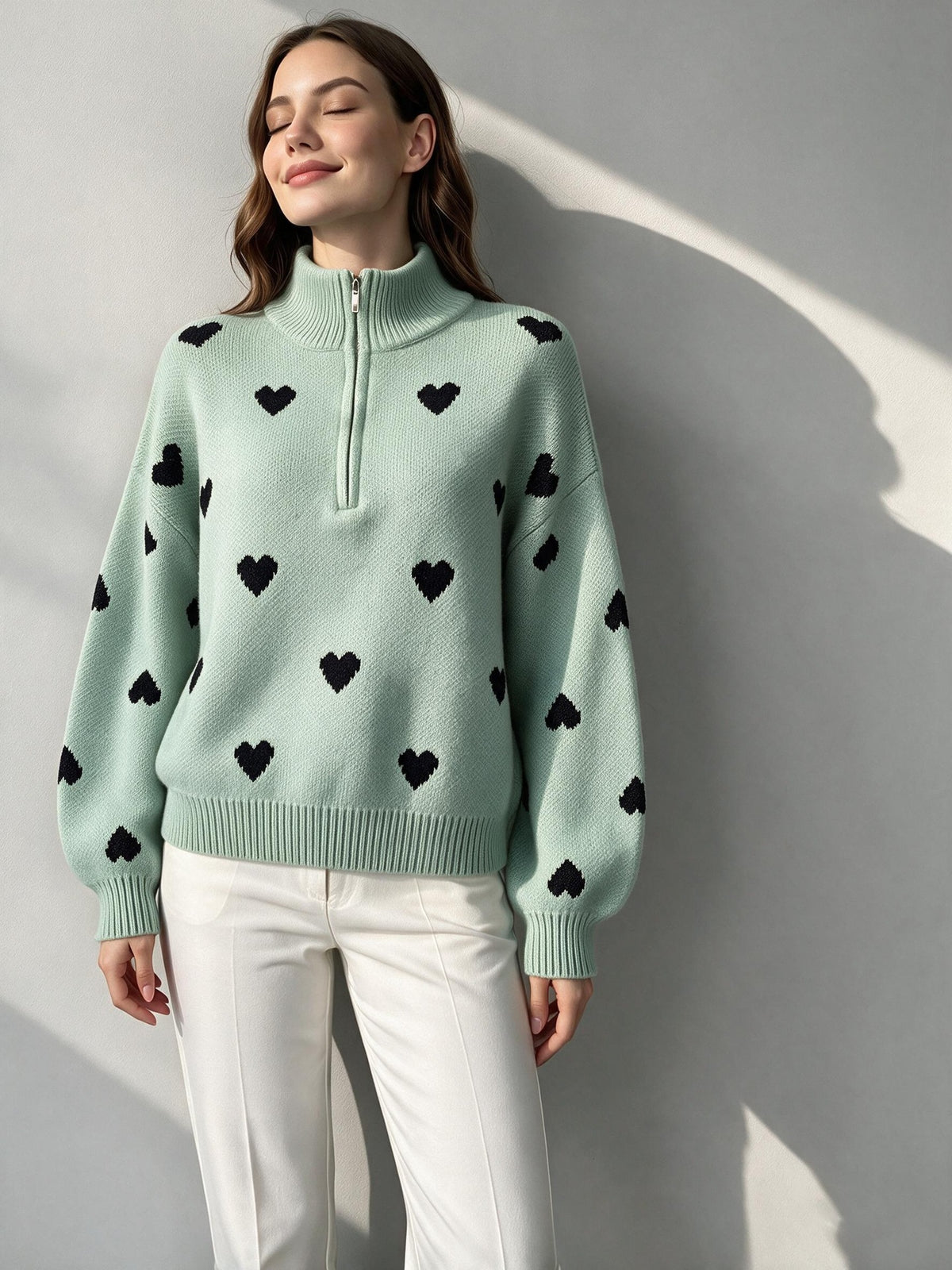Light green heart-pattern sweater with a zip-up high neck and ribbed trim.