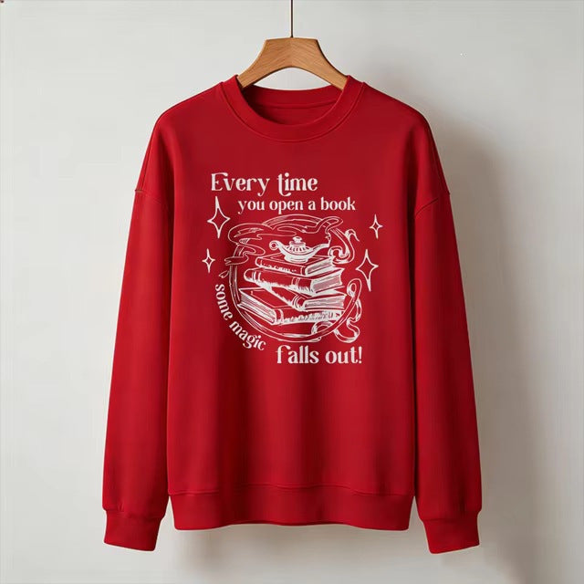 Red crewneck sweatshirt with open-book magic graphic and starry text, long sleeves.