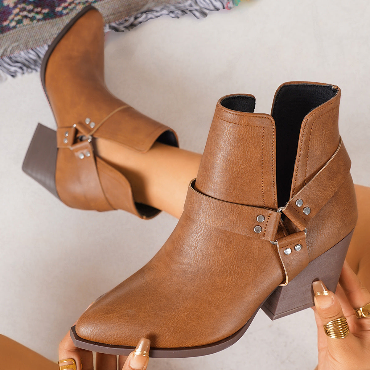 Brown leather-look ankle boots with side buckles, decorative straps, and block heel