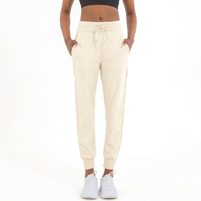 Cream jogger pants with drawstring waist, side pockets, and tapered ankle cuffs